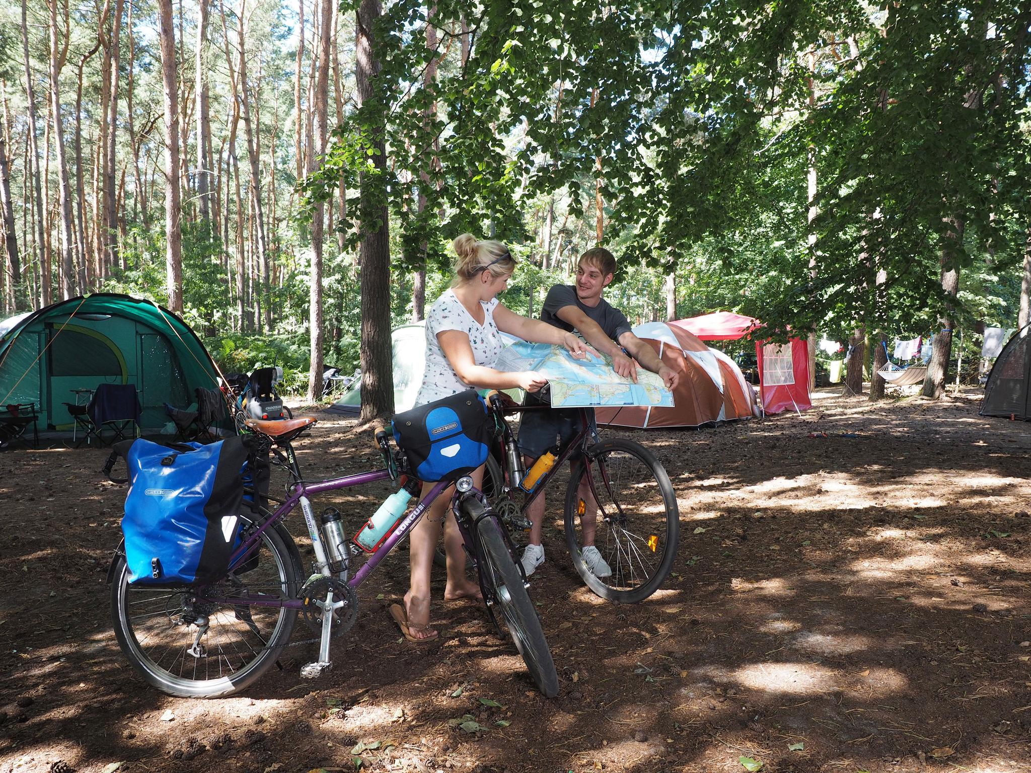 Pärchen mit Fahrrädern auf einem Campingplatz im Wald