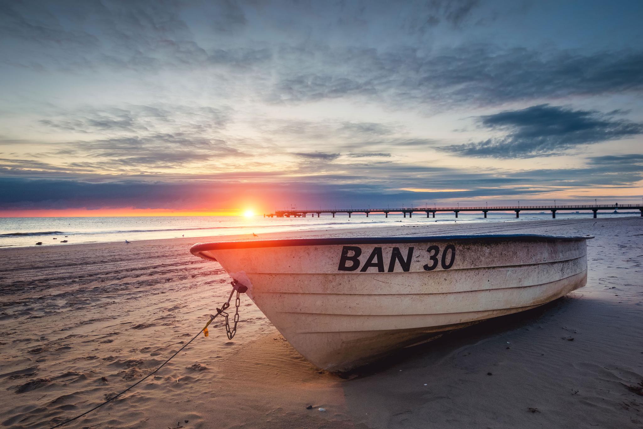 Das Bild zeigt ein Fischerboot am Strand von Bansin auf Usedom. Im Hintergrund ist die Seebrücke zu erkennen.