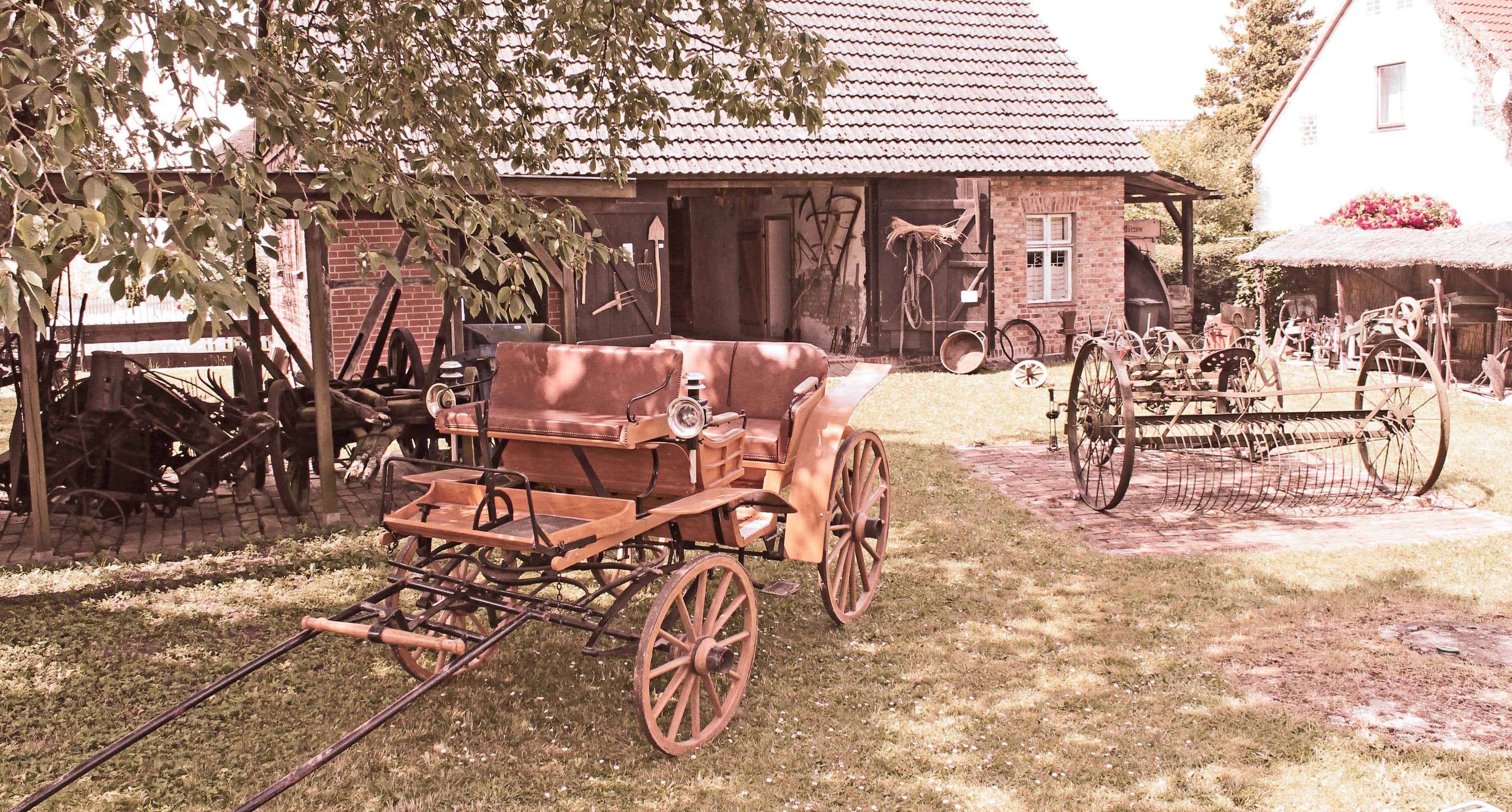 historische Fuhrwerke vor einer Scheune 