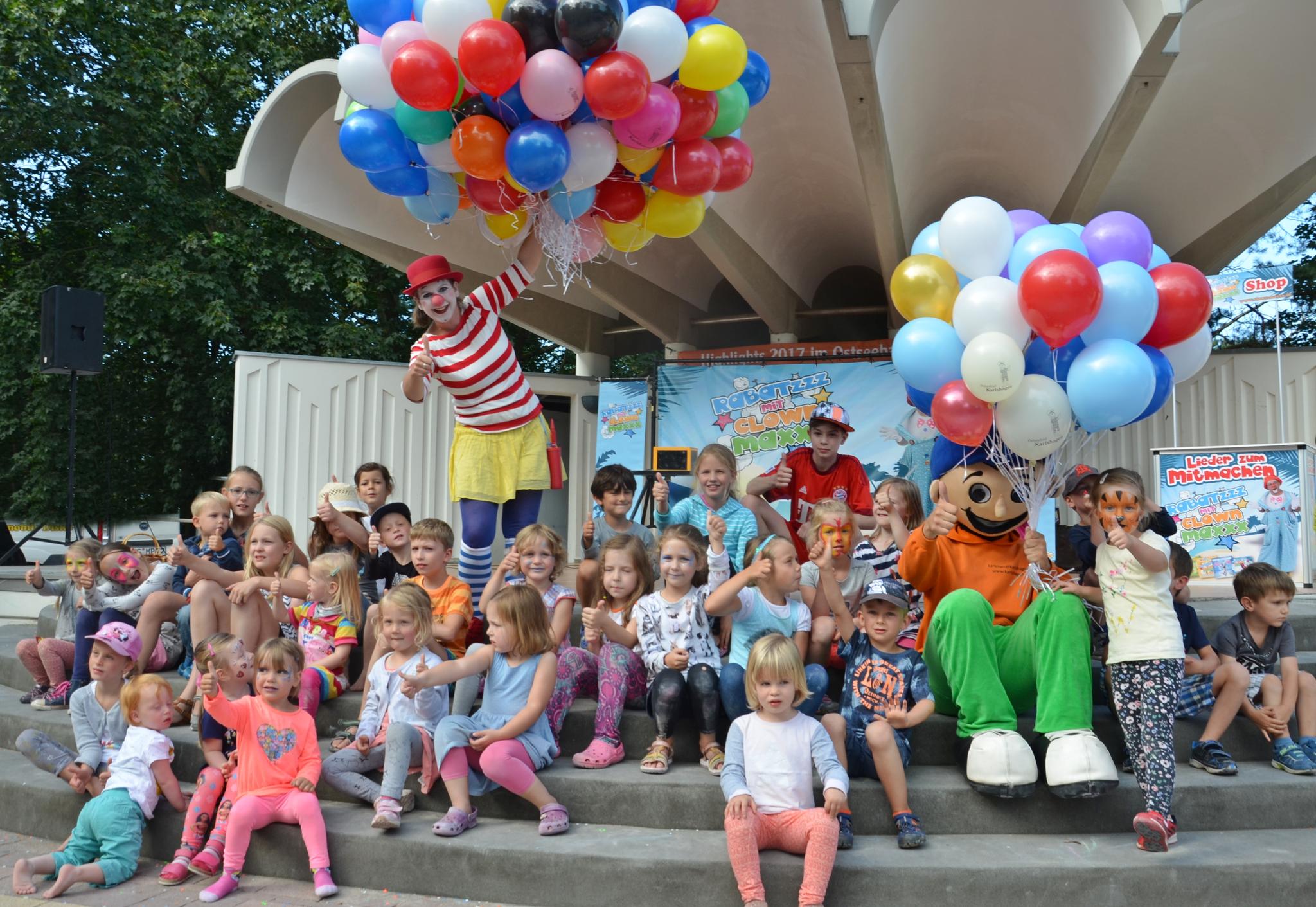 Das Bild zeigt ein Kinderfest mit dem Maskottchen Karlchen an der Konzertmuschel in Karlshagen.