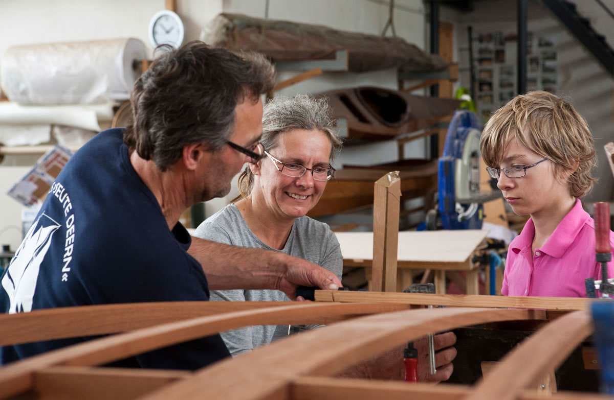 Personen in einer Werkstatt beim Holzboot bauen