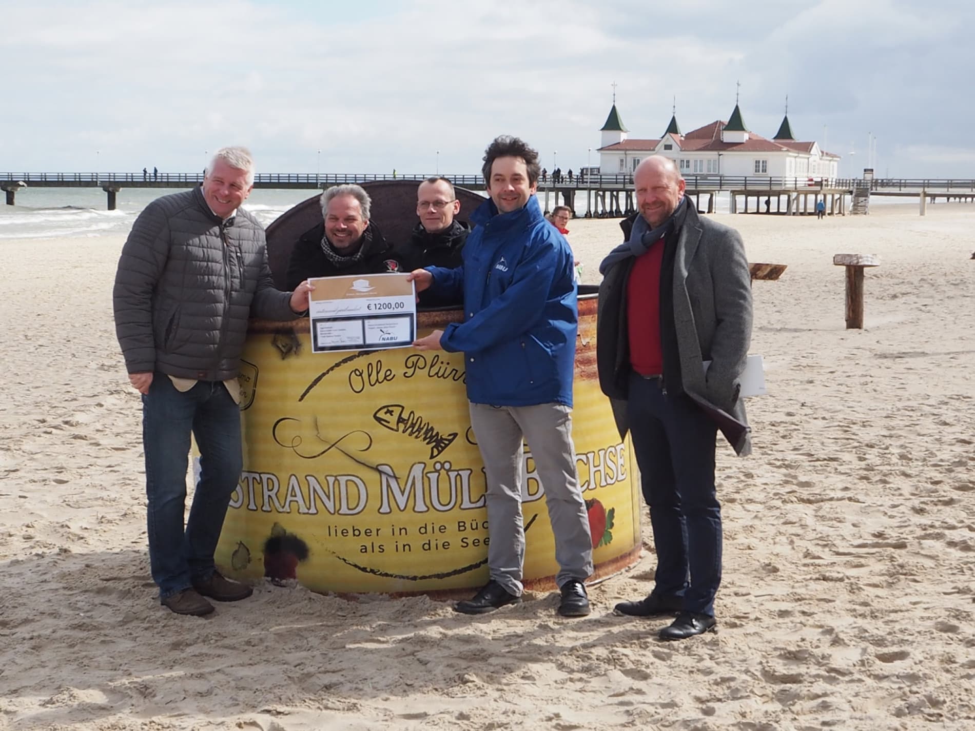 Personen am Strand vor Ahlbecker Seebrücke bei Spendenscheck-Übergabe