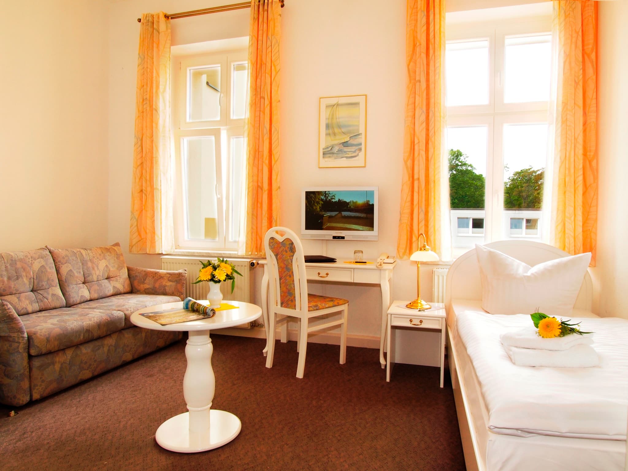 Einzelzimmer mit Bett, Tisch, Sofa und TV