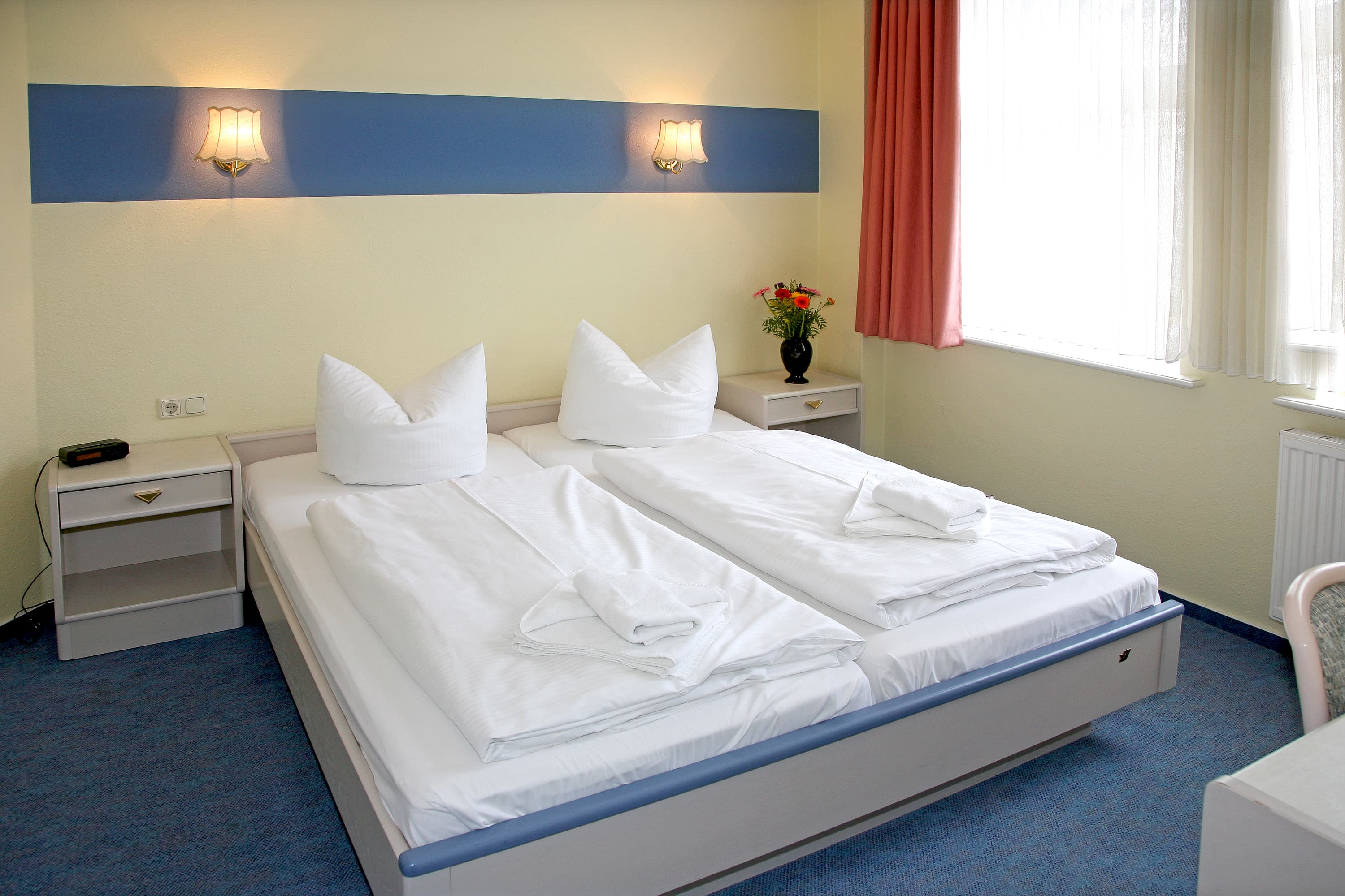 Doppelzimmer mit gelben Wänden und blauem Teppich