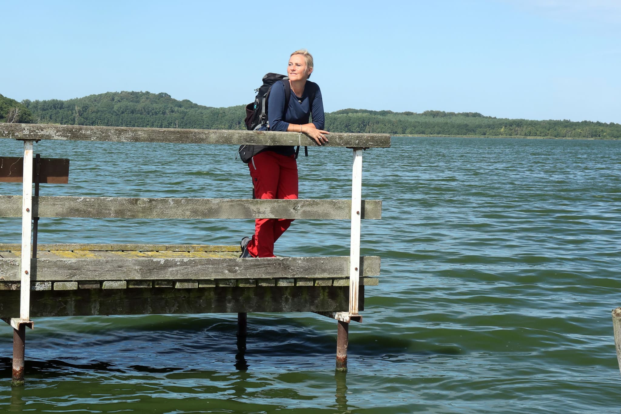 Frau steht auf einem Steg am See. 