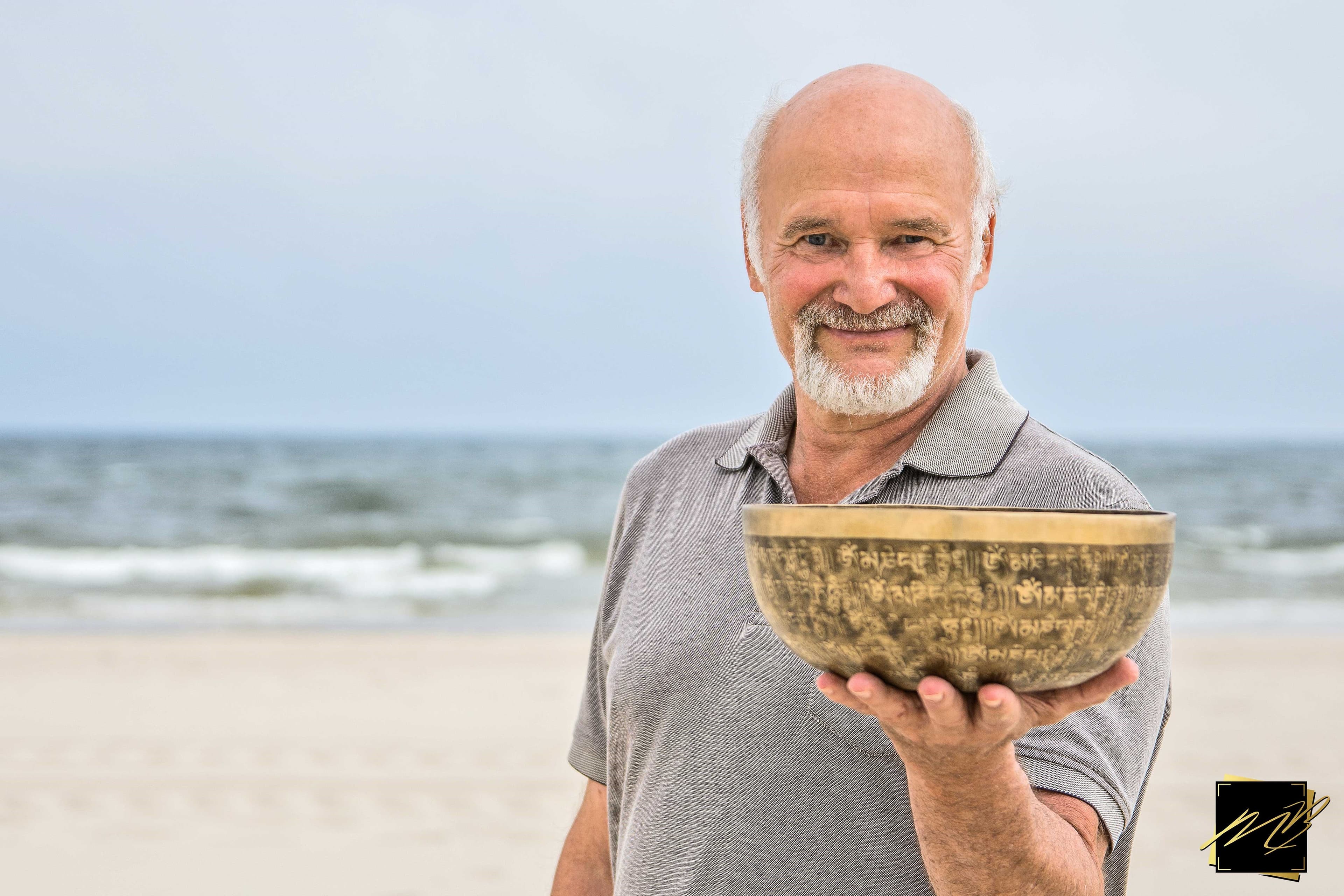 Mann mit einer Klangschale am Strand