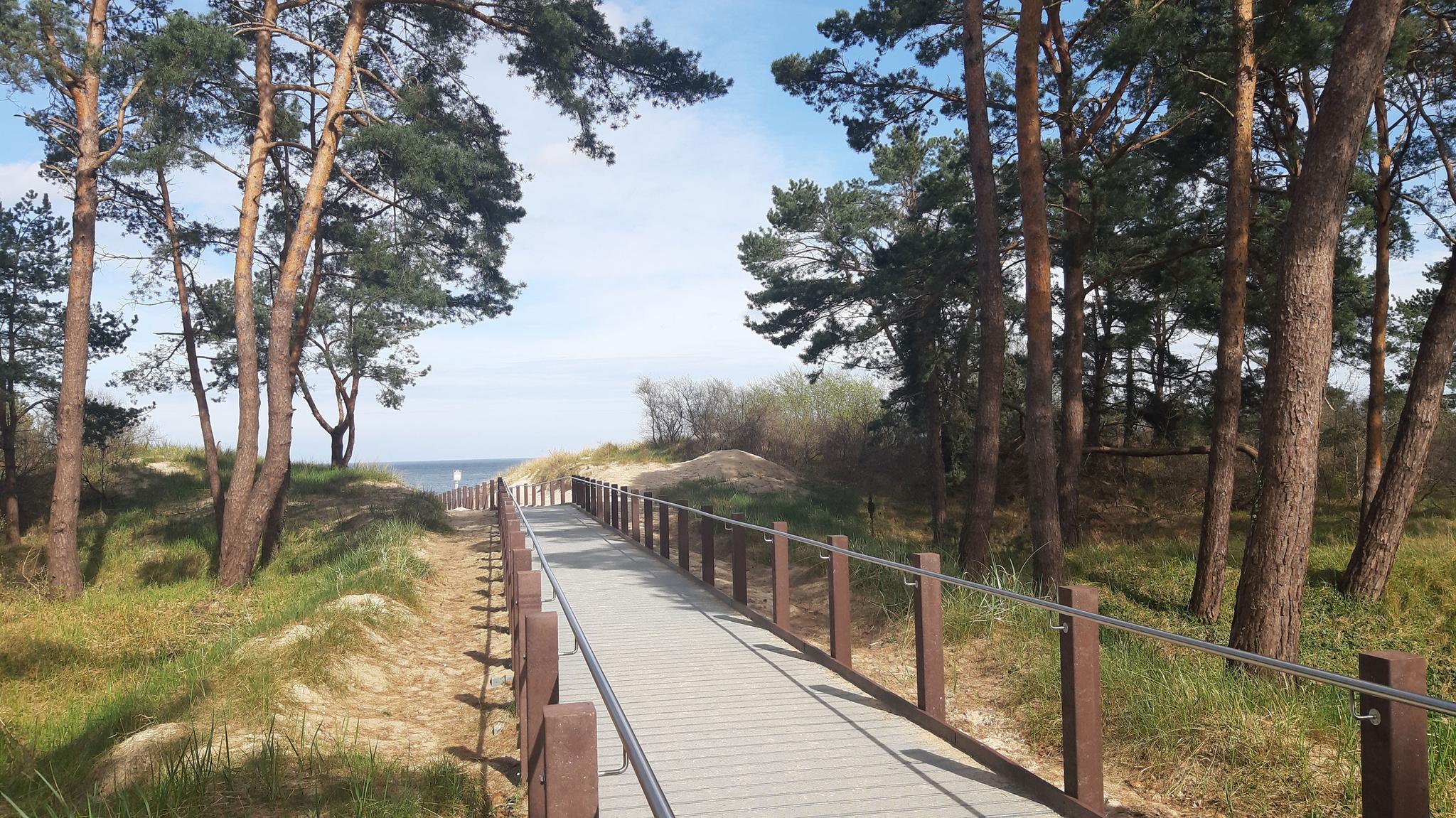 befestigter Holzweg mit Geländer, der zum Strand führt