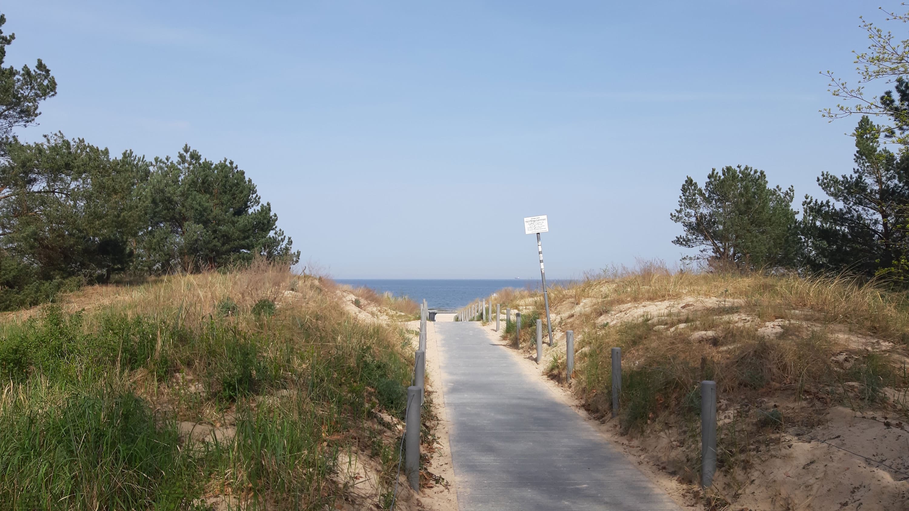 schmaler befestigert Holzweg, der zum Strand führt