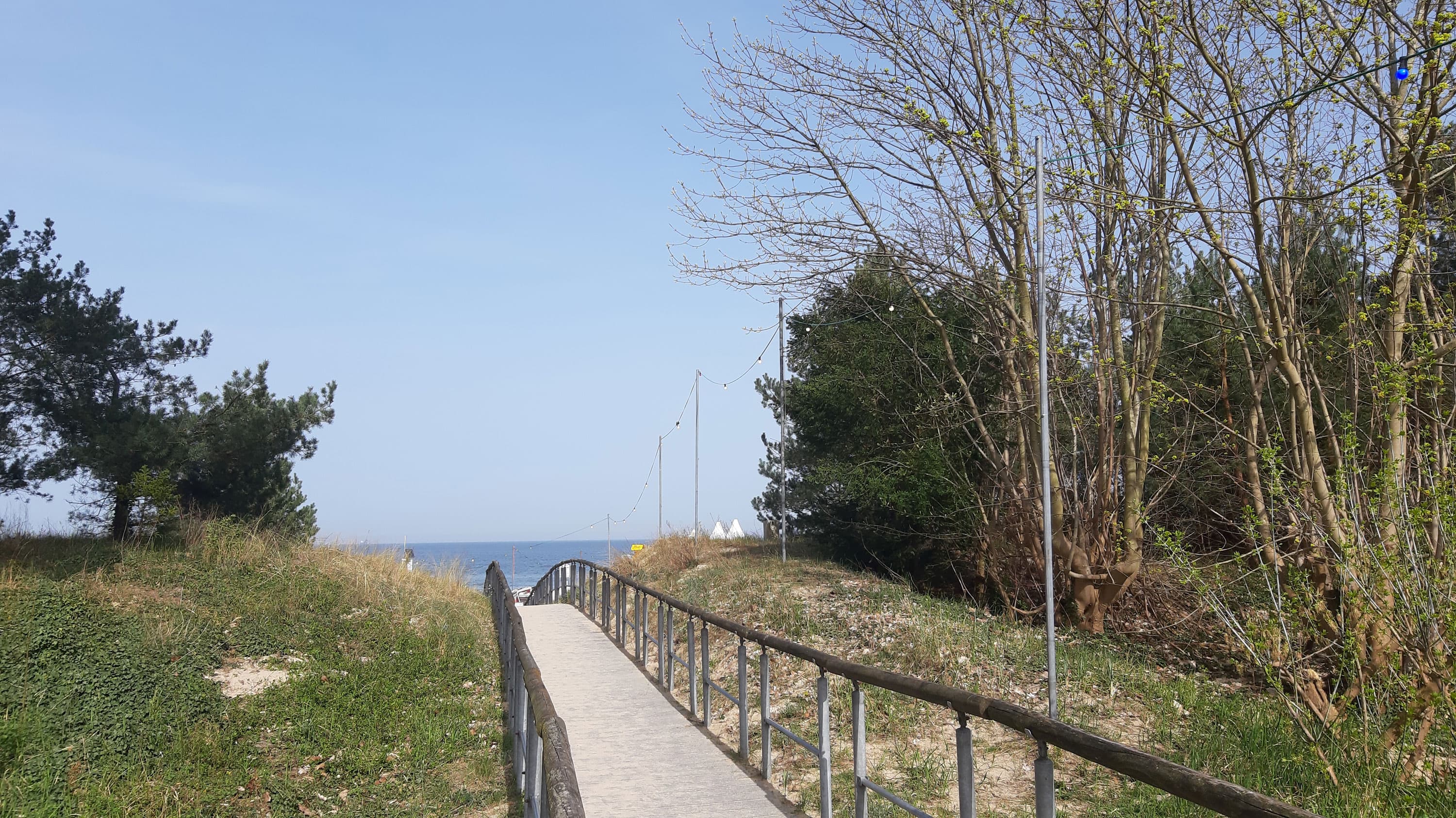 befestigter Holzweg mit Geländer, der zum Strand führt