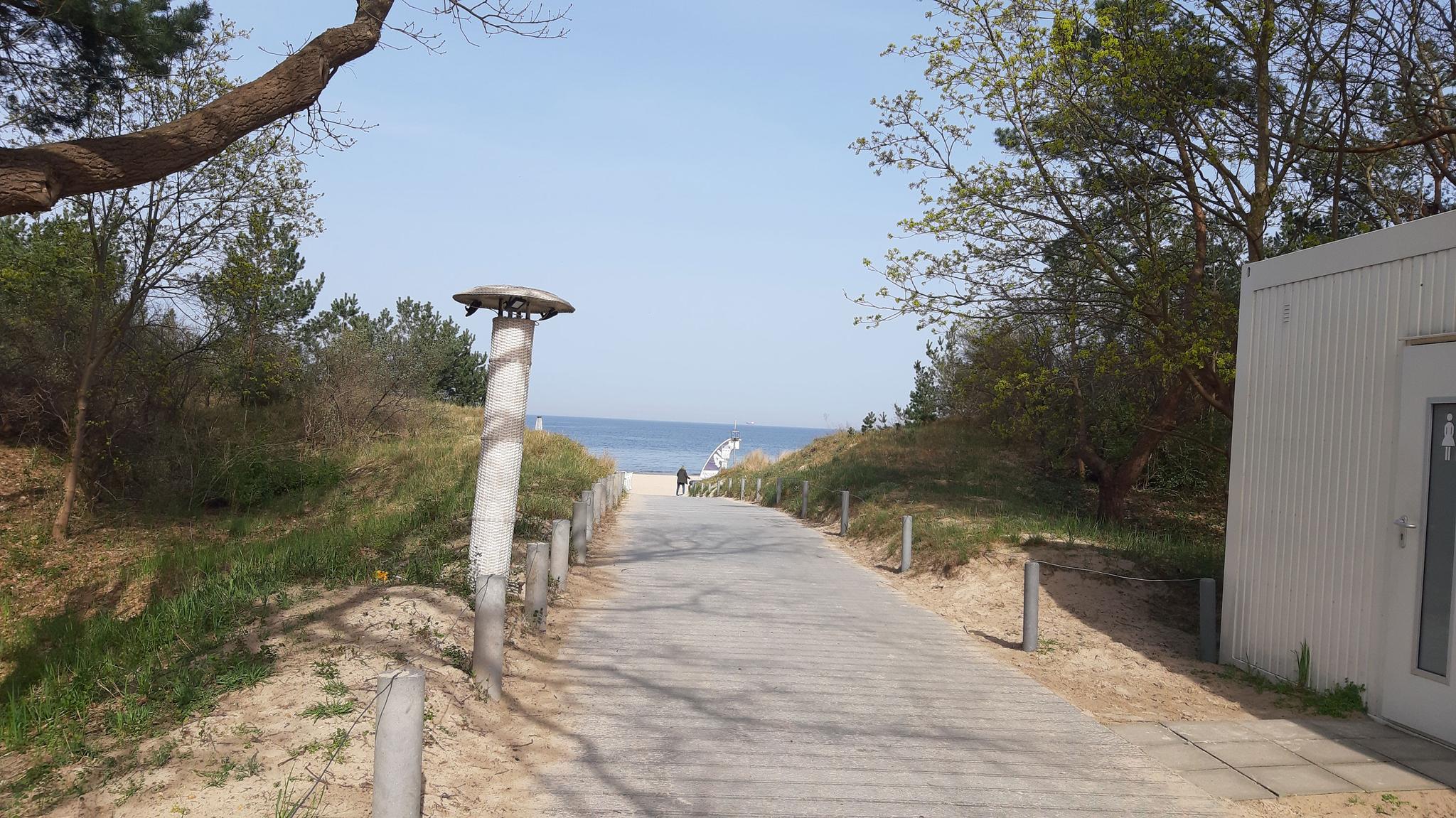 breiter befestigter Holzweg, der zum Strand führt