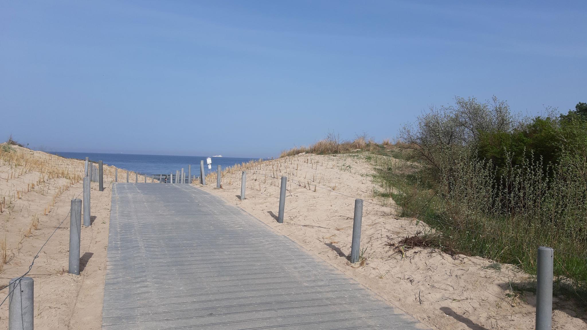 breiter befestigter Holzweg, der zum Strand führt