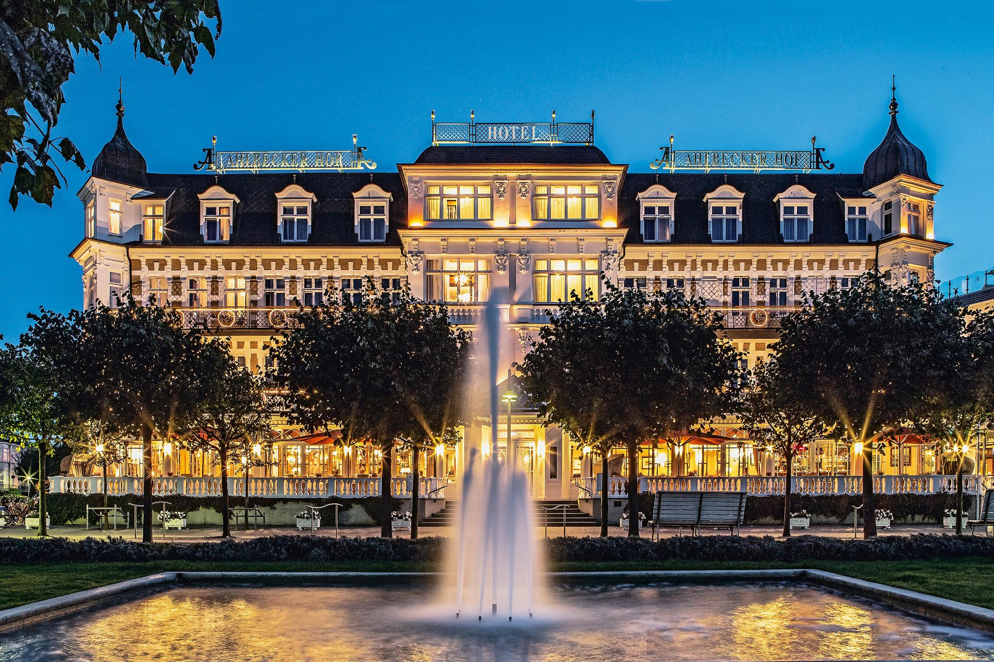 Beleuchtetes Hotel von aussen mit Springbrunnen im Vordergrun