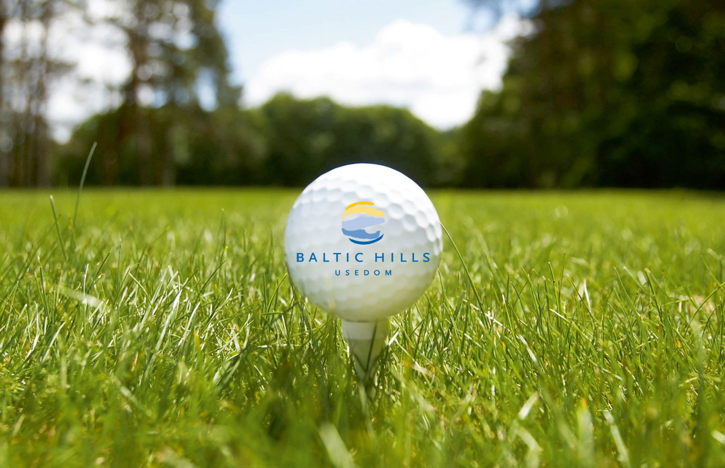 schöne grüne Wiese, in der Mitte ist ein Golfball mit dem Baltic Hills Logo