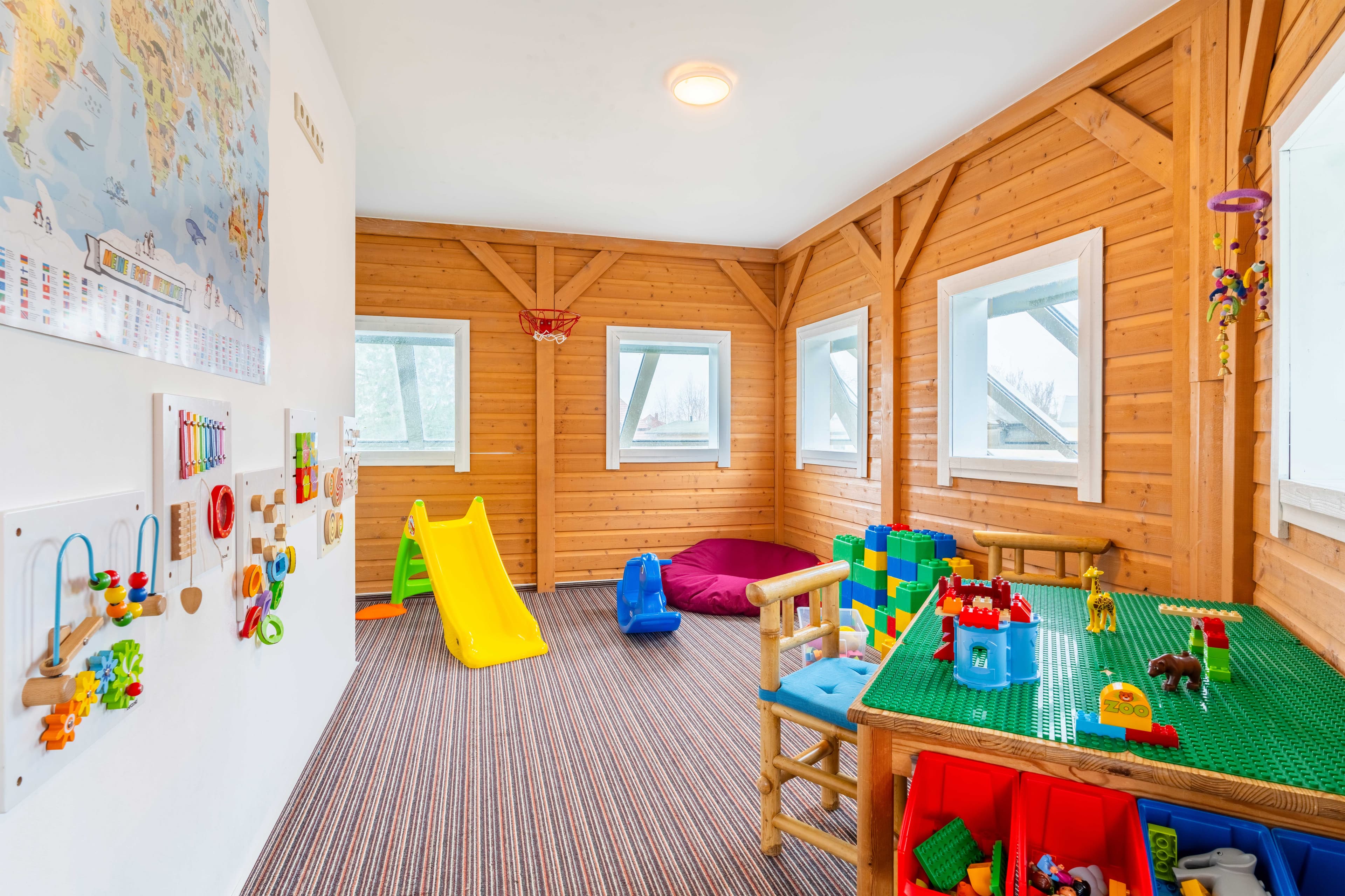 ein bunter Spielraum für Kinder mit Sitzgruppe, Rutsche und diversem Spielzeug