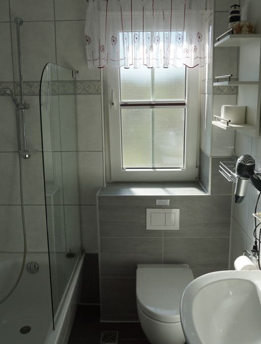 Duschbadewanne, Toilette und Waschbecken, Fenster über der Toilette, Haartrockner an der Wand