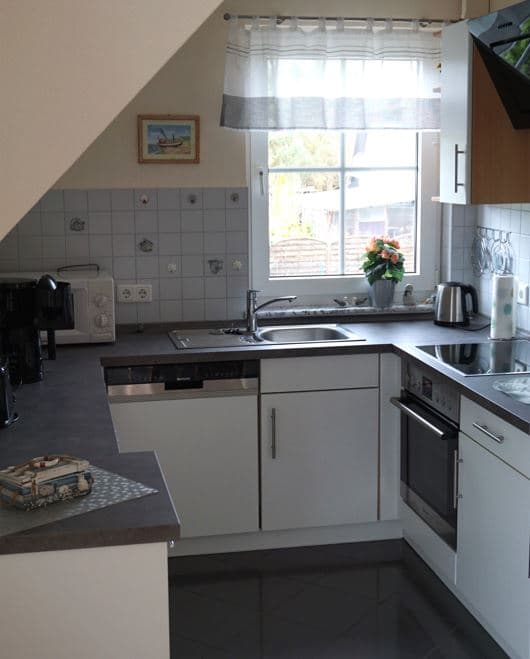 Gerämige Einbauküche mit Fenster, Spülmaschine, Backofen und Herd, Spüle und Wasserkocher