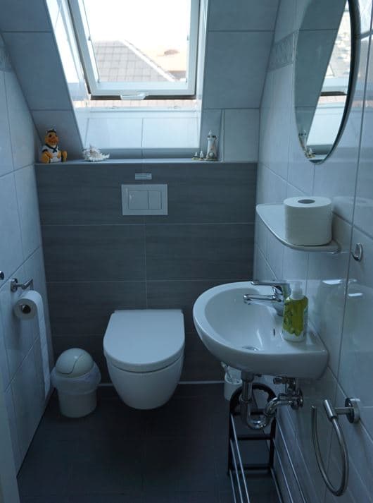 Gästetoilette mit Dachfenster und Waschbecken, sowie rundem Spiegel über dem Waschbecken