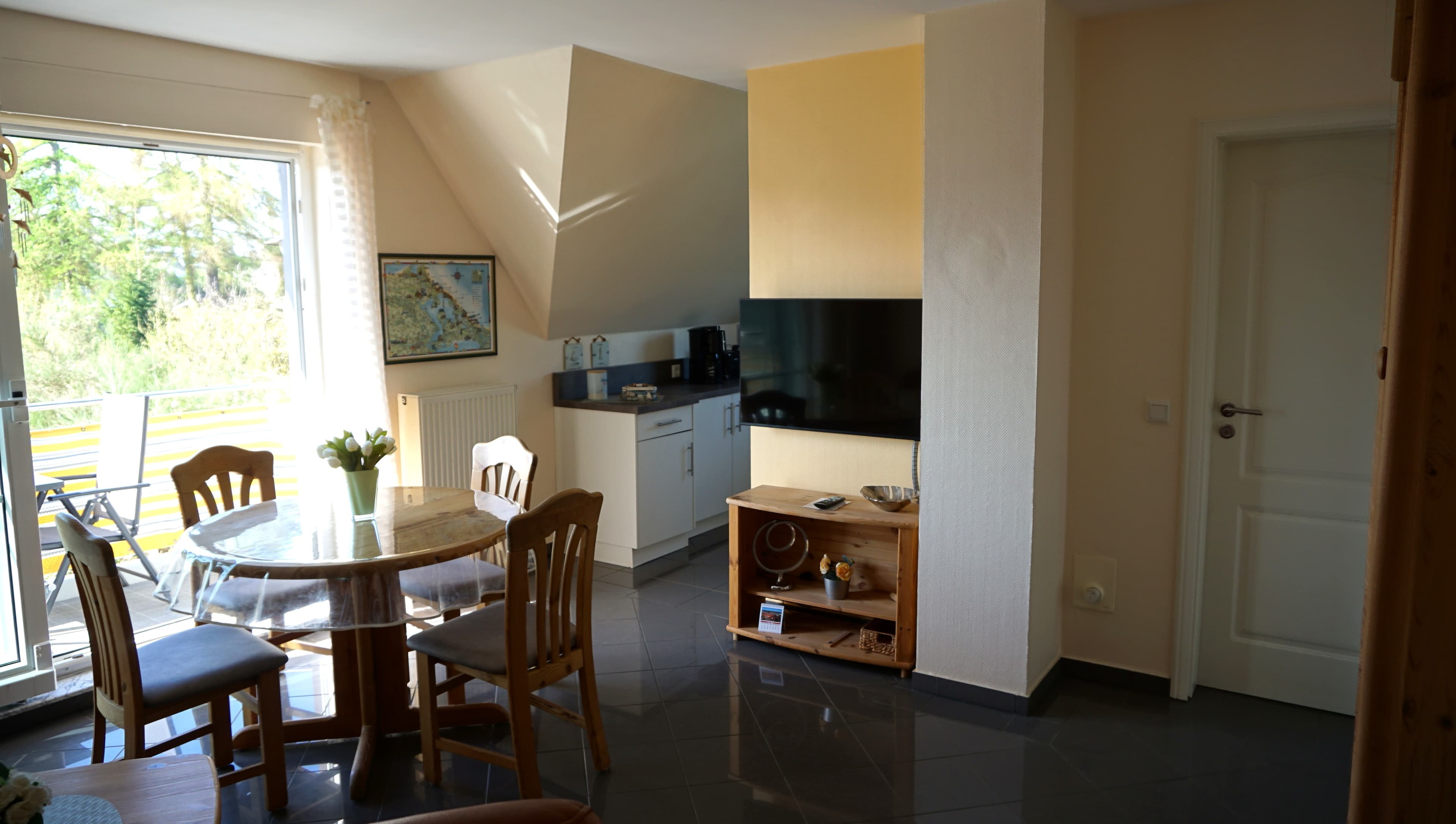 Wohnküche mit Panoramafenster zum Balkon, TV-Gerät und Tür