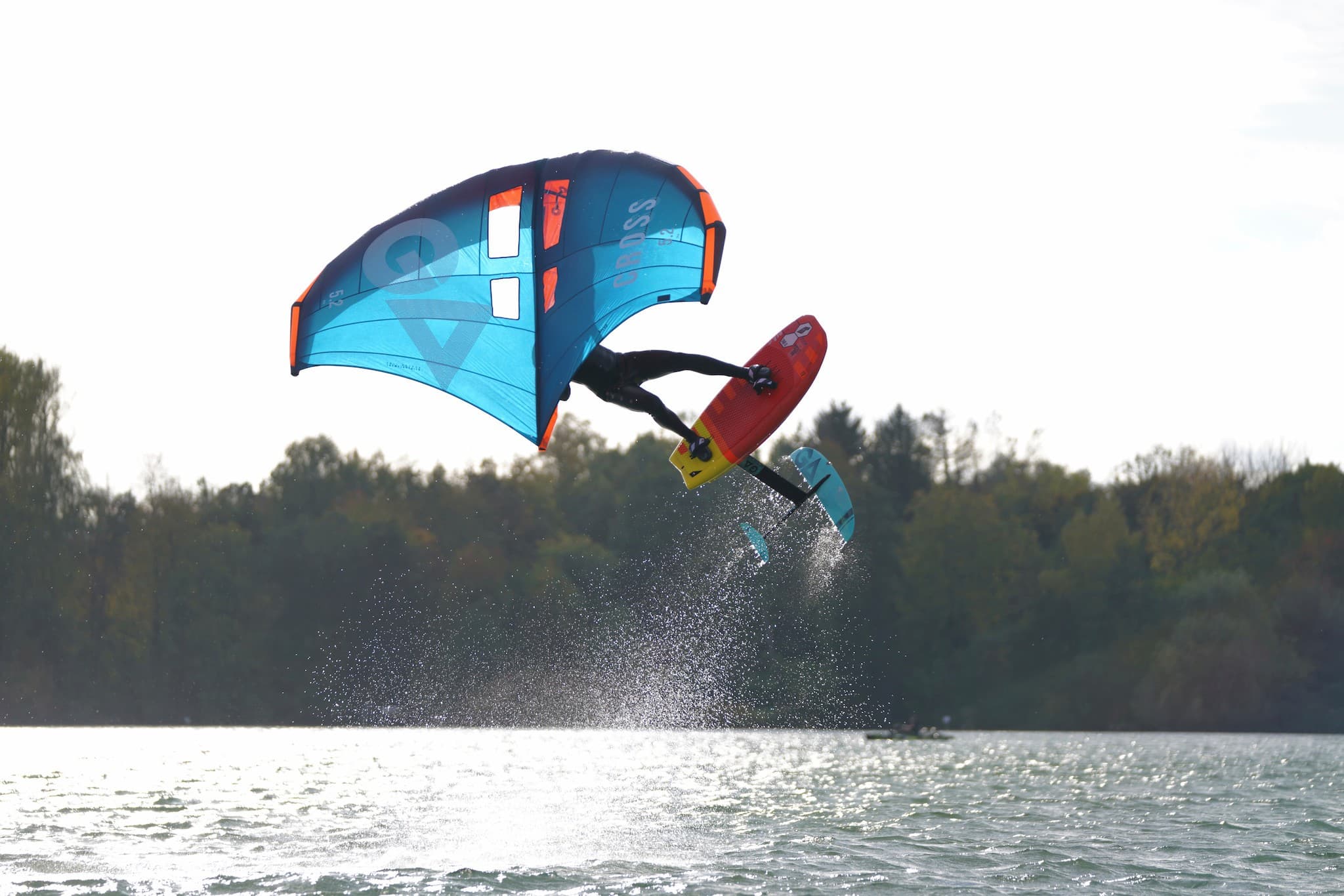 Ein Wingsurfer springt in gleißendem Sonnenlicht aus dem Wasser