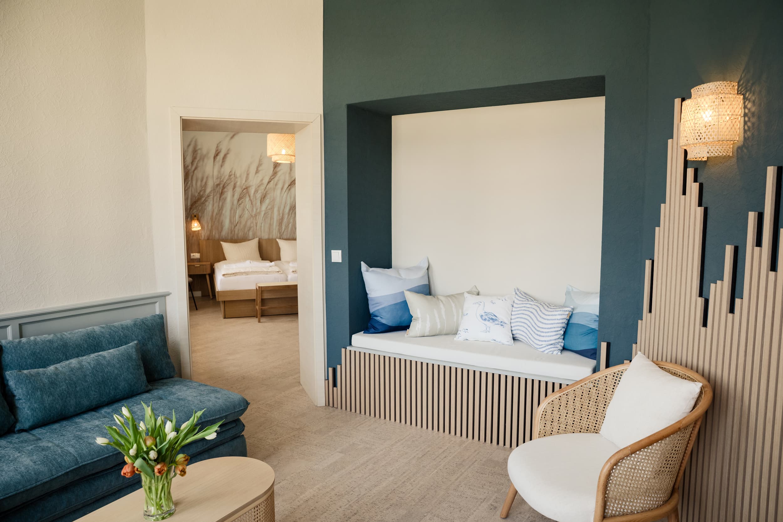 gemütlich eingerichtetes Zimmer mit einem bleuen Sofa und eienm beigen Stuhl