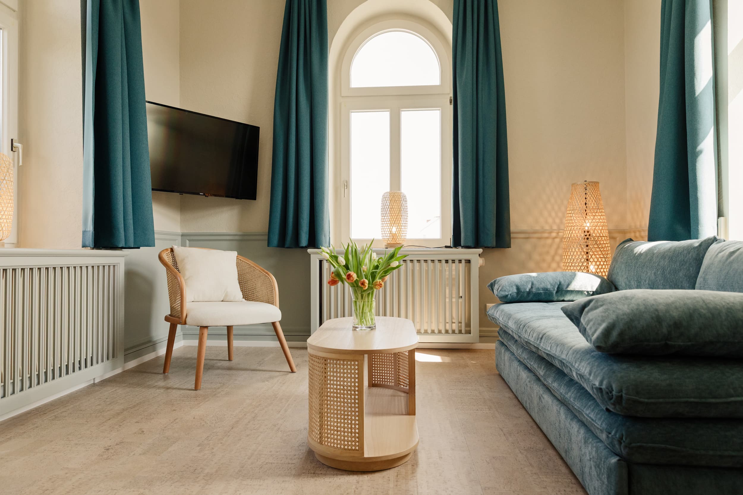 gemütliches Zimmer mit einem beigen Beistelltisch und einem Fernseher an der Wand 