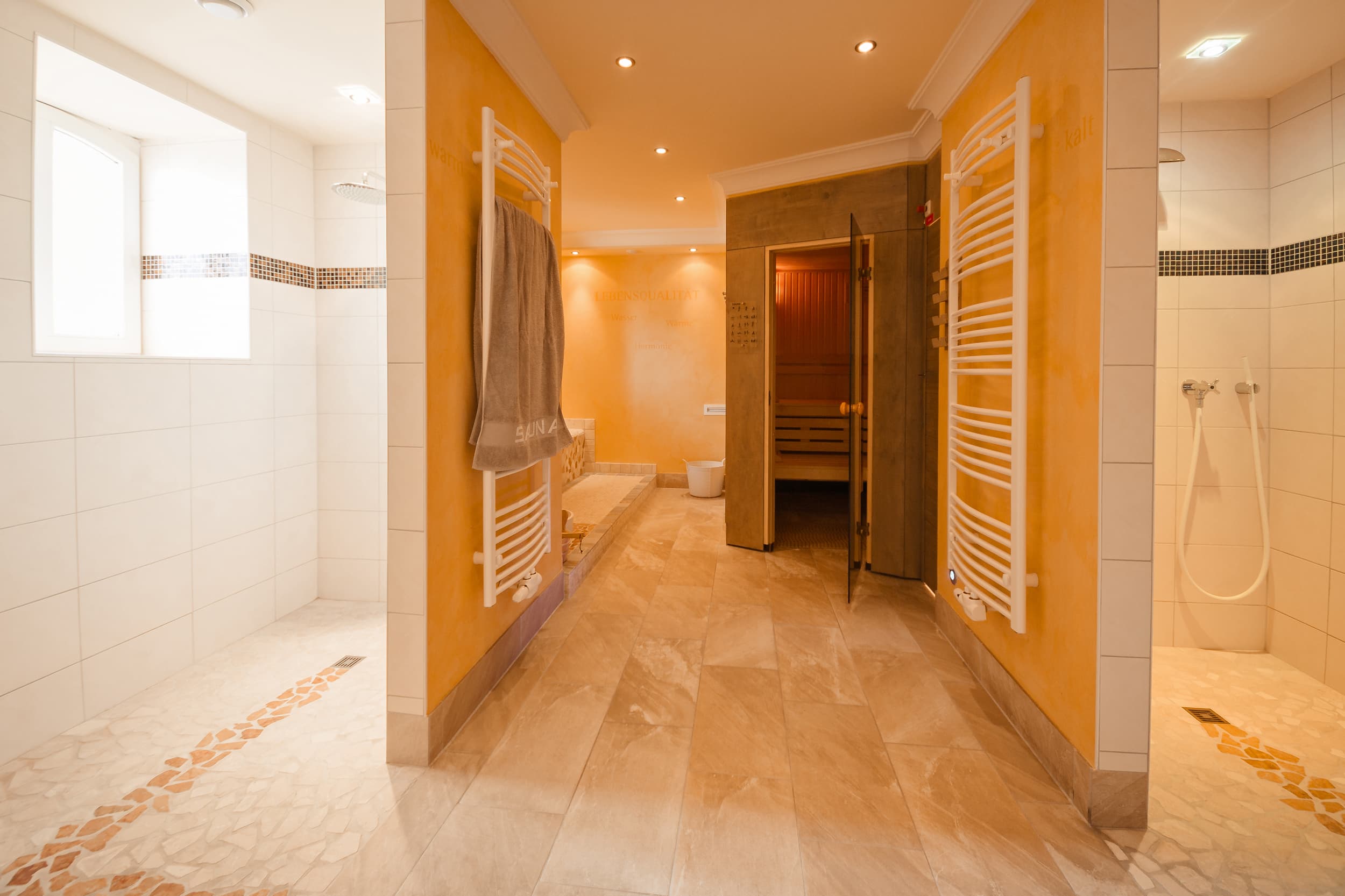 Beige gefliester Eingang zu einer Sauna mit lichtdurchfluteten Fluren