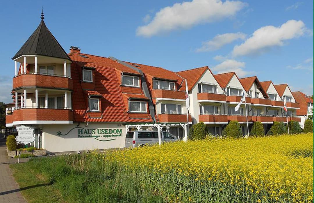 längliches Gebäude mit vielen Fenstern und Balkonen, rotes Dach