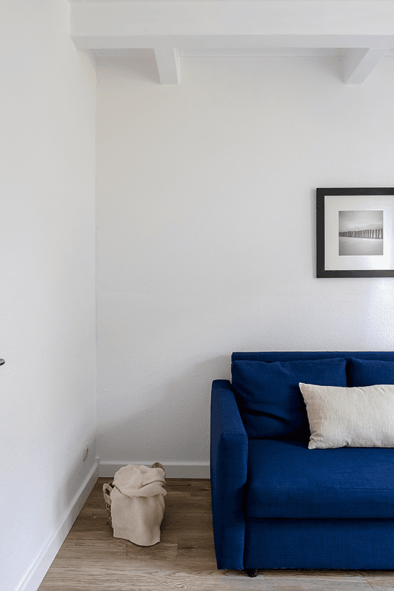 dunkelblaue Couch mit weißem Kissen vor weißer Wand
