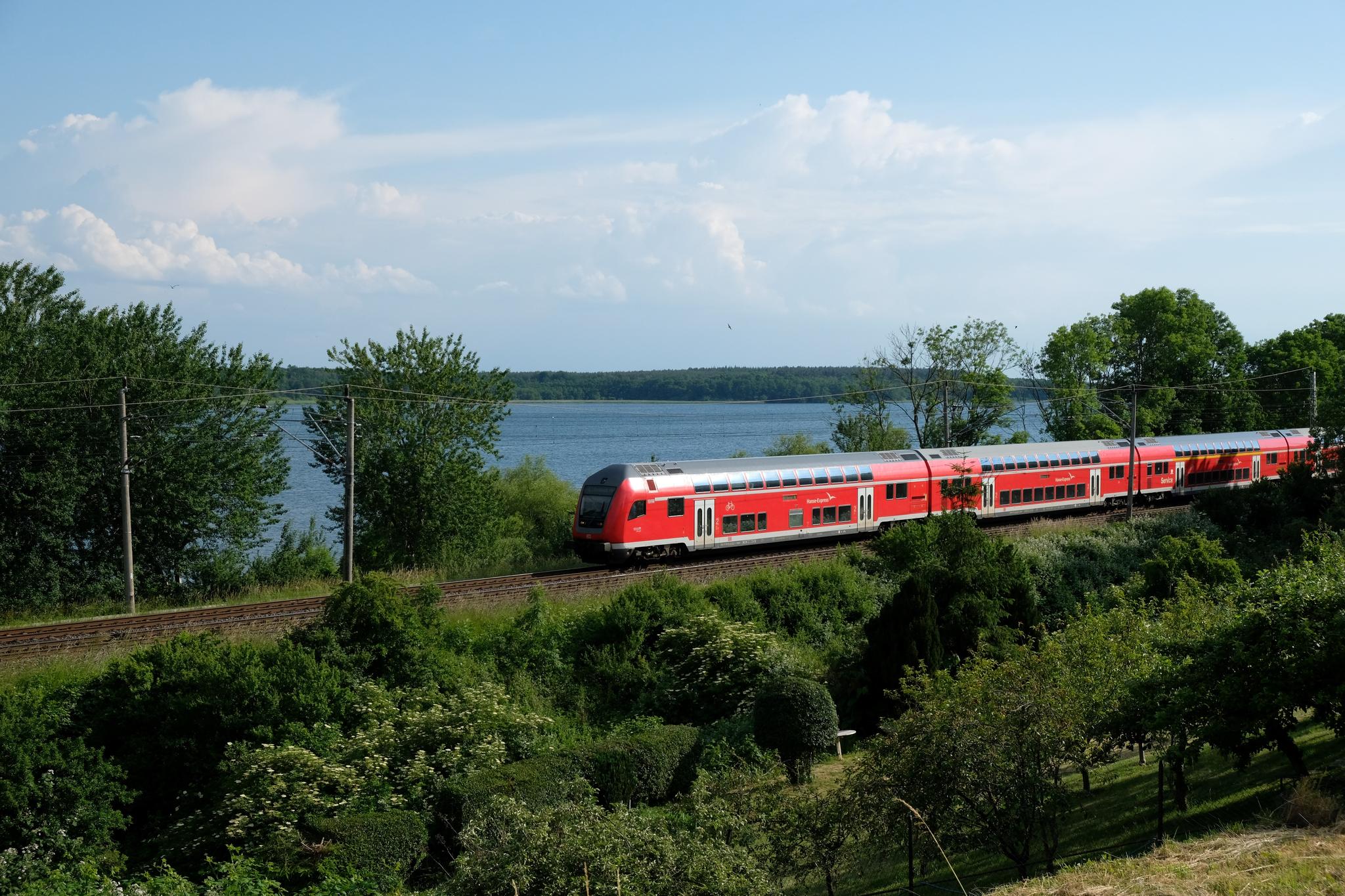 Roter Zug fährt an Gewässer vorbei