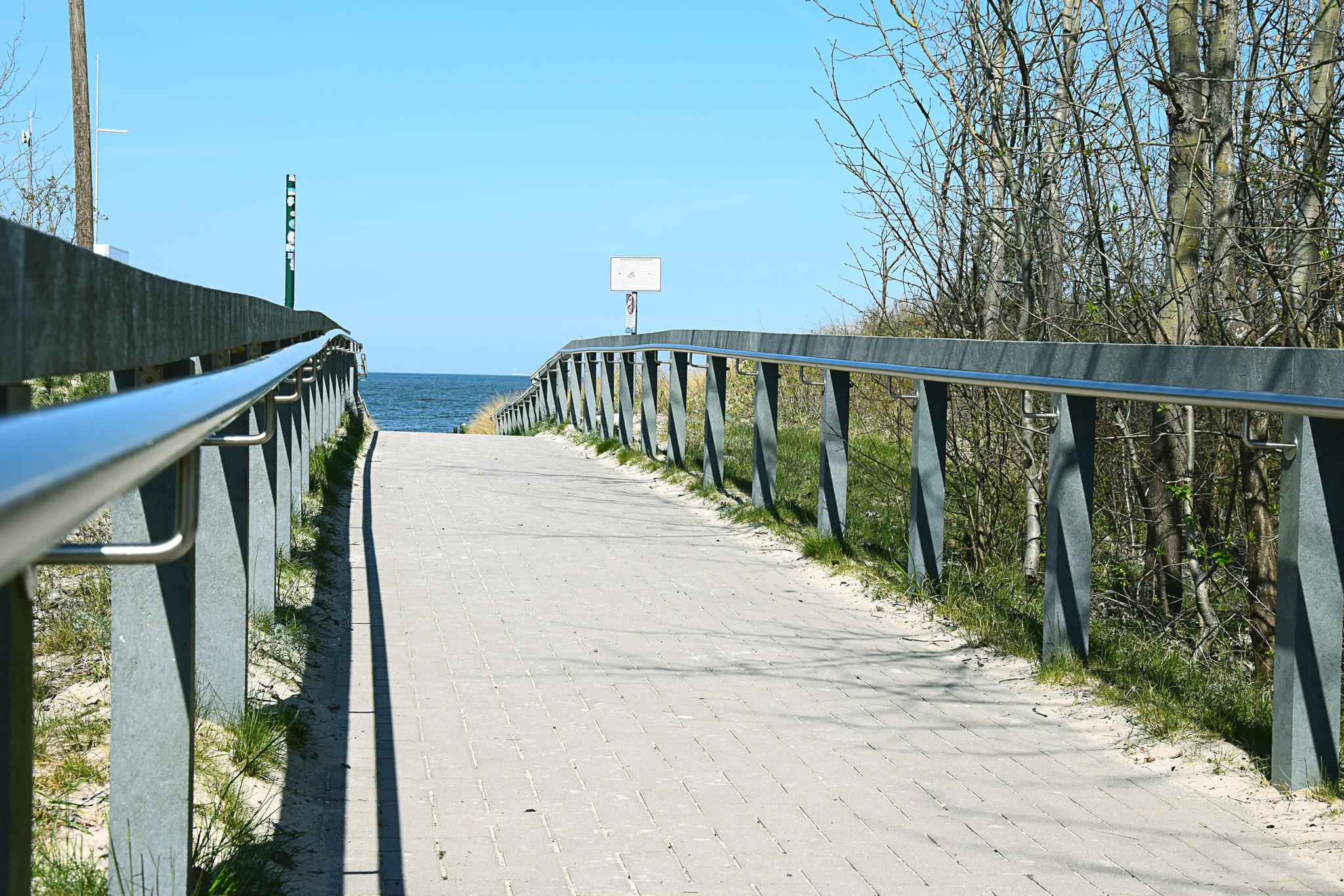 Ein befestigter Weg mit Handlauf führt zum Strand.