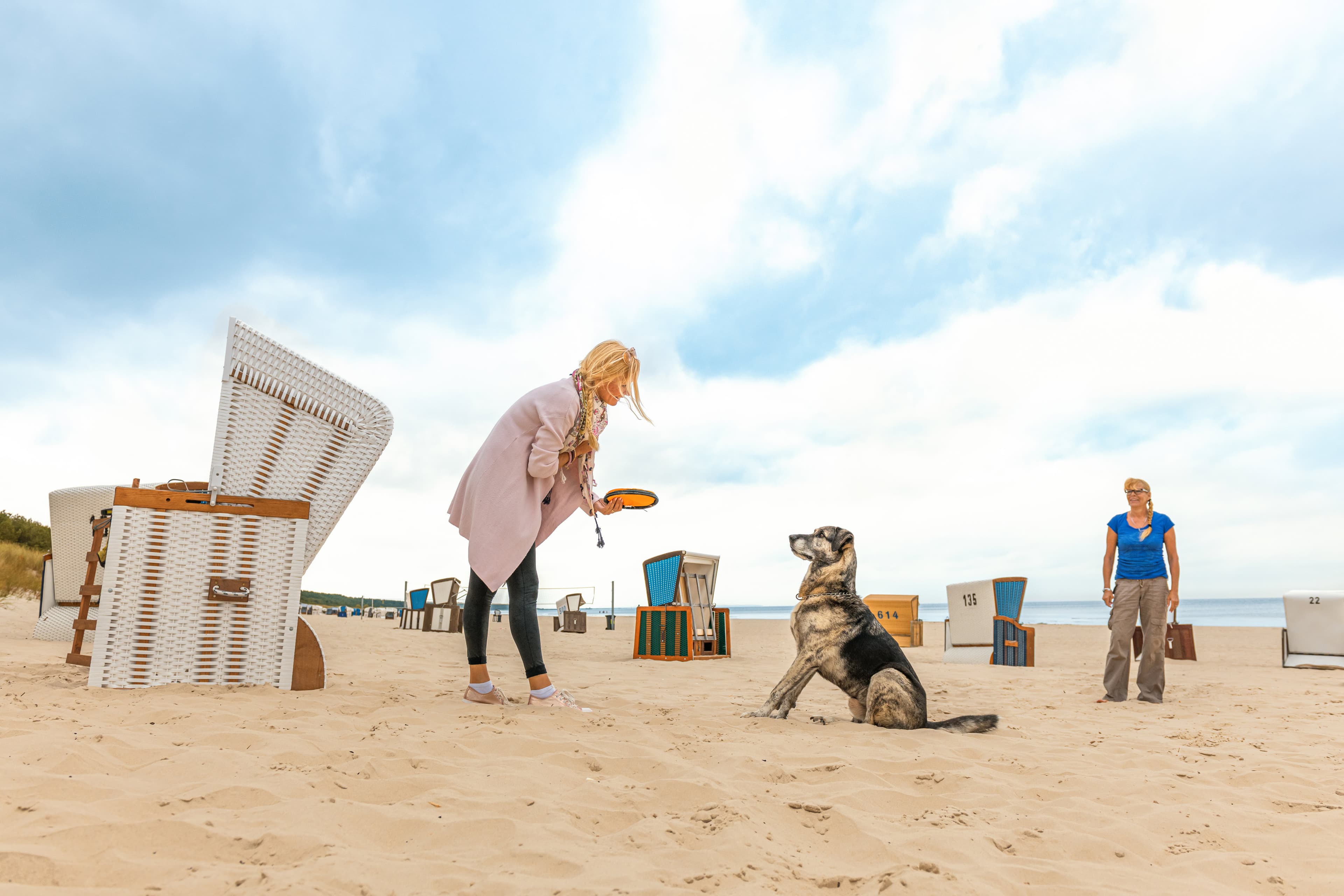 Frau spielt mit Hund am Strand