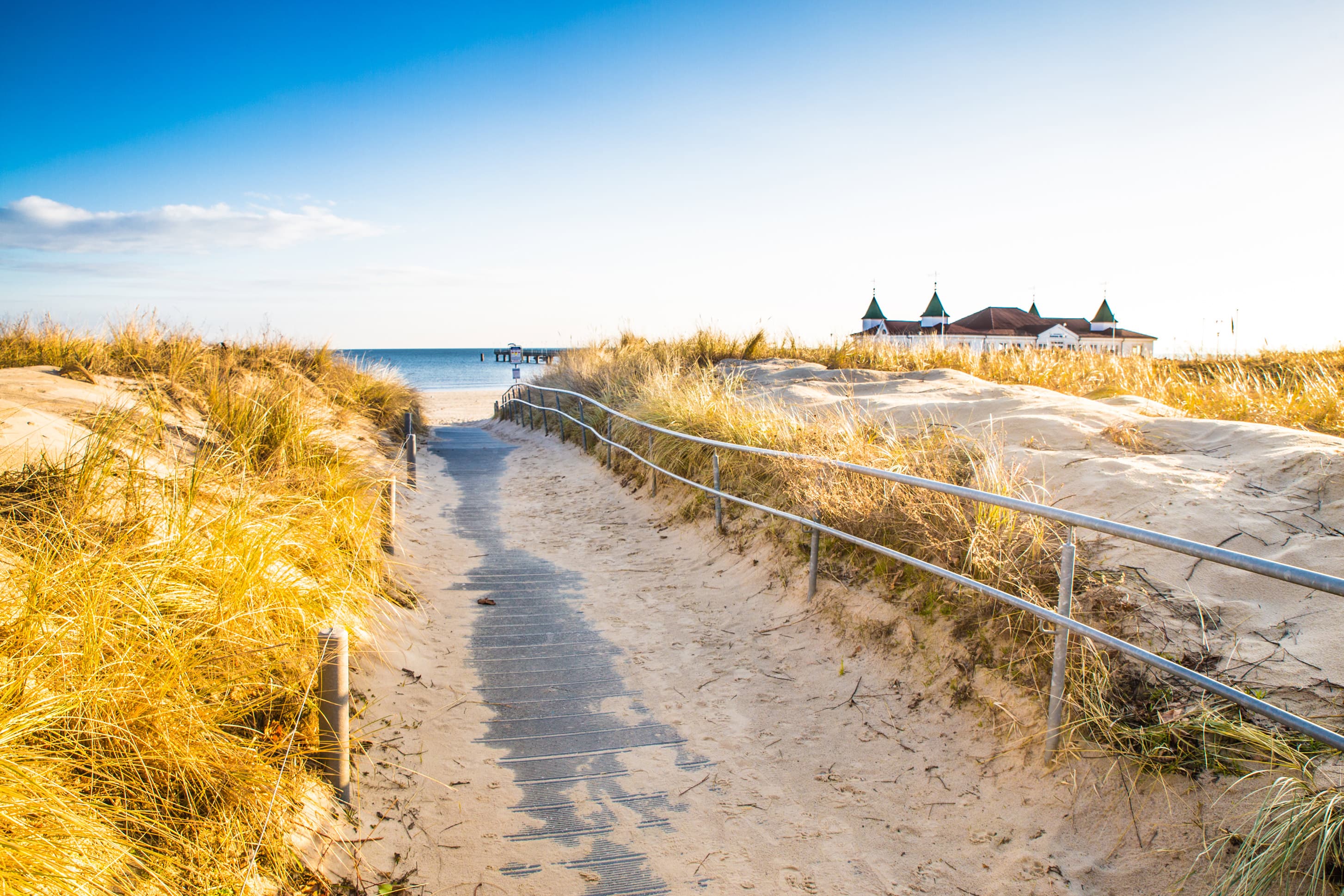 Strandaufgang mit blauem Himmel und der Ahlbecker Seebrücke im Hintergrund