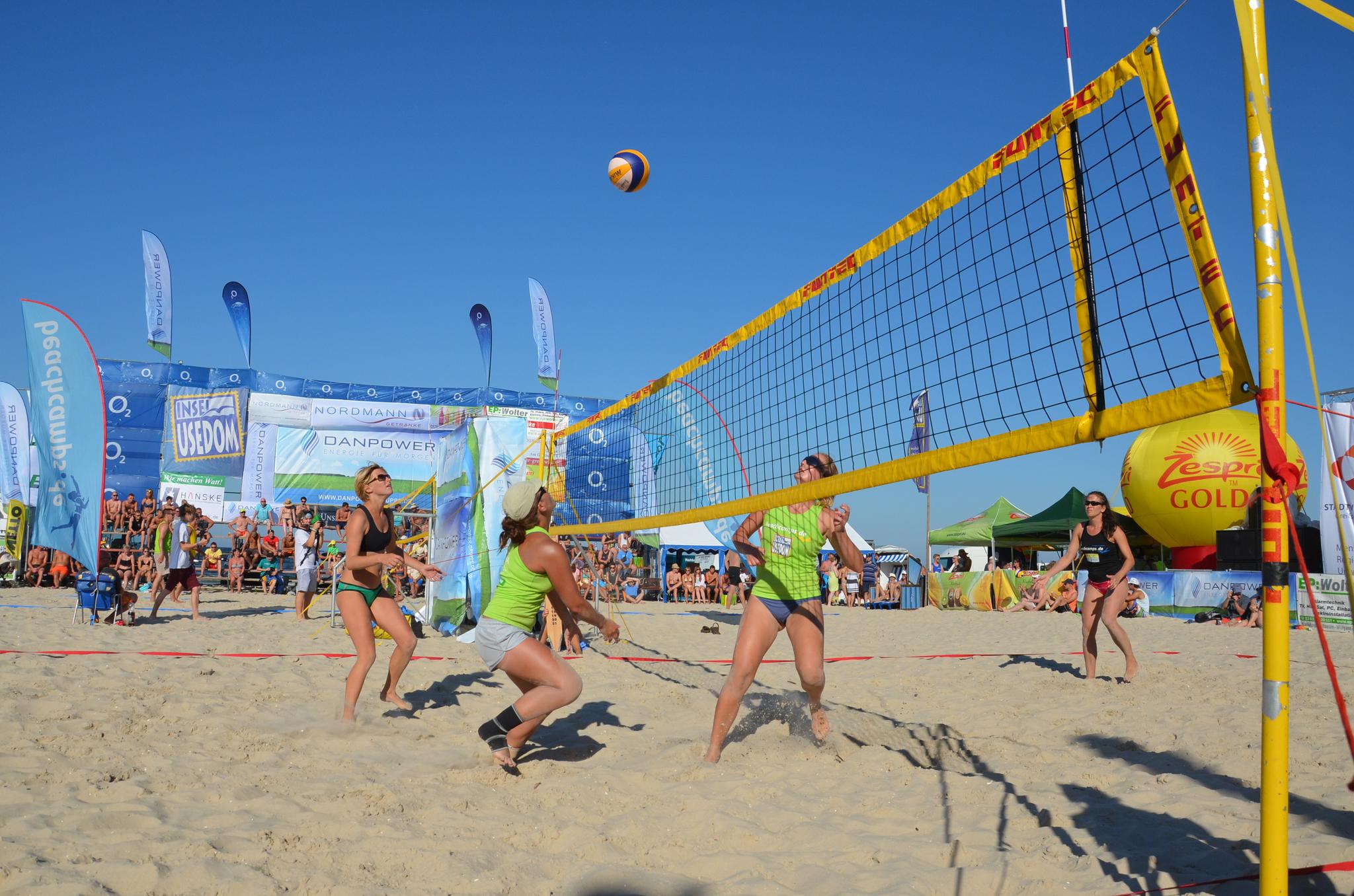 Mehrere Personen beim Volleyball spielen am Strand mit Publikum im HIntergrund