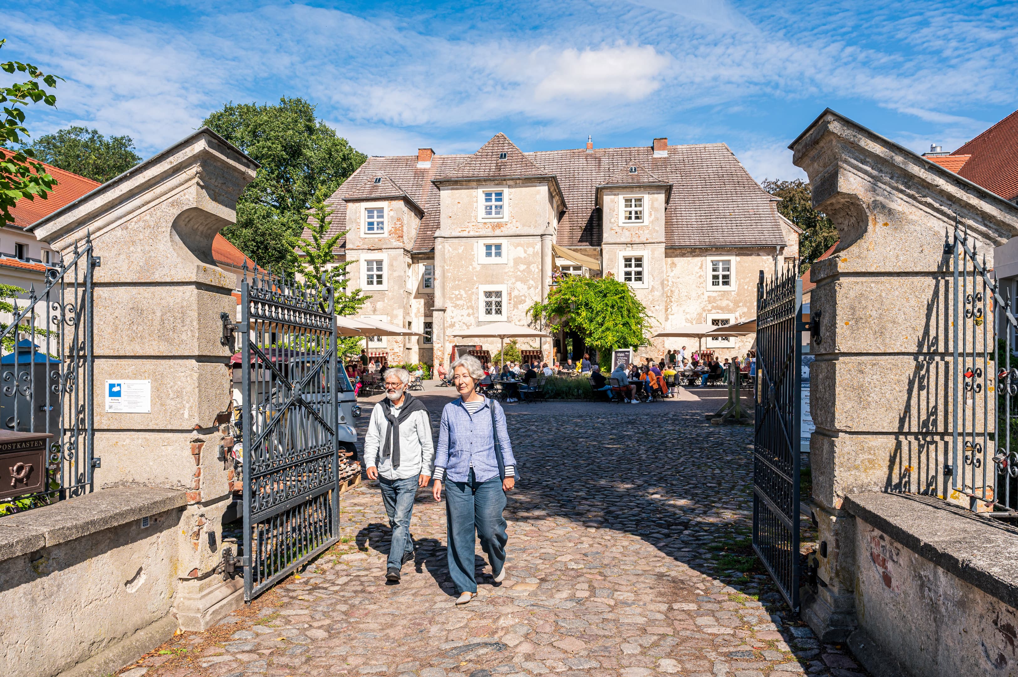 Pärchen läuft durch das Eingangstor vom Wasserschloss Mellenthin