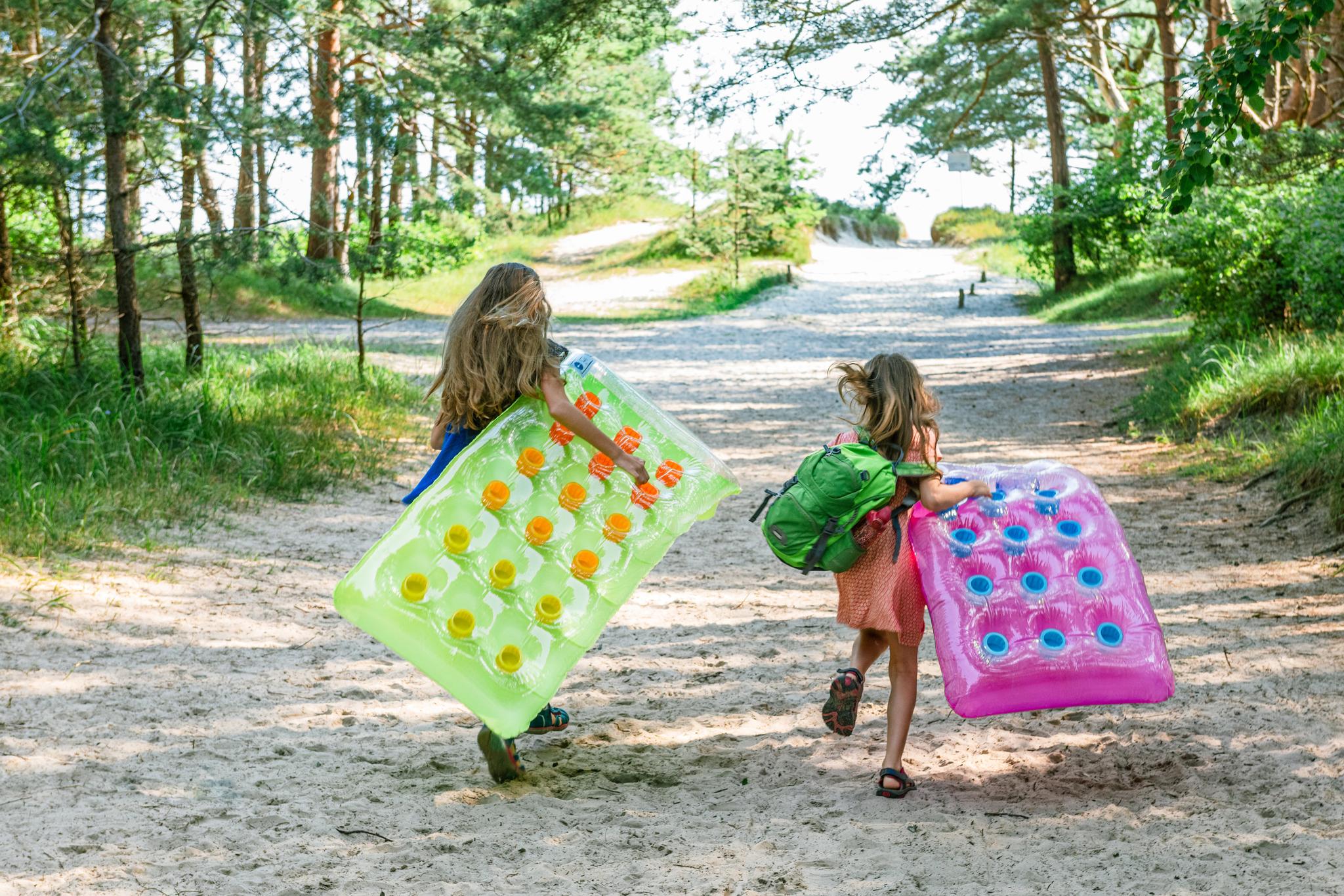 Das Bild zeigt zwei Kinder mit ihren Lutfmatratzen auf dem Weg zum Strand in Peenemünde