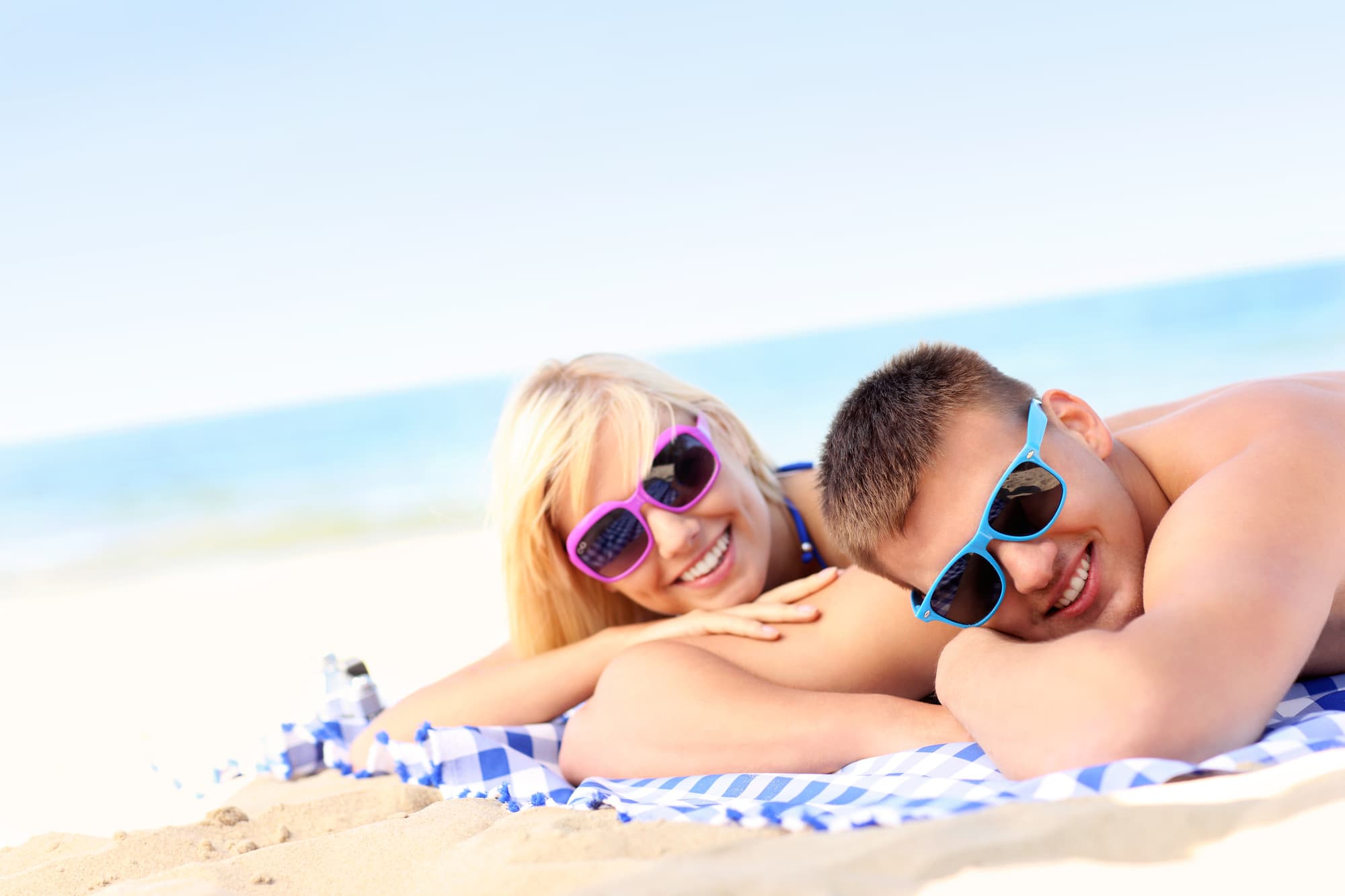 Pärchen liegt am Strand mit Sonnenbrillen