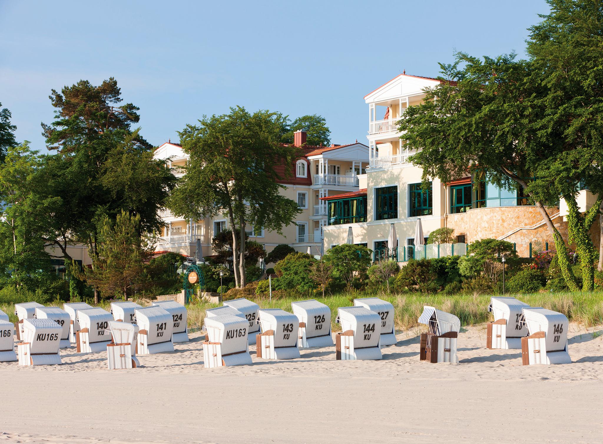 Strandkörbe am Strand mit "Travel Charme Hotel" im Hintergrund