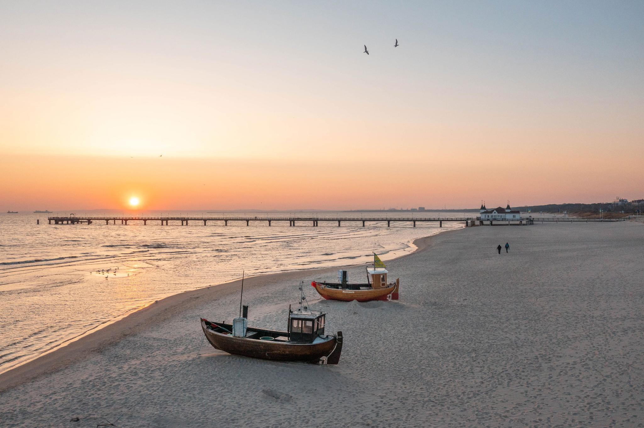 Am Strand von Ahlbeck liegen 2 Fischerboot und im Hintergrund ragt die Seebrücke in die Ostsee hinaus.