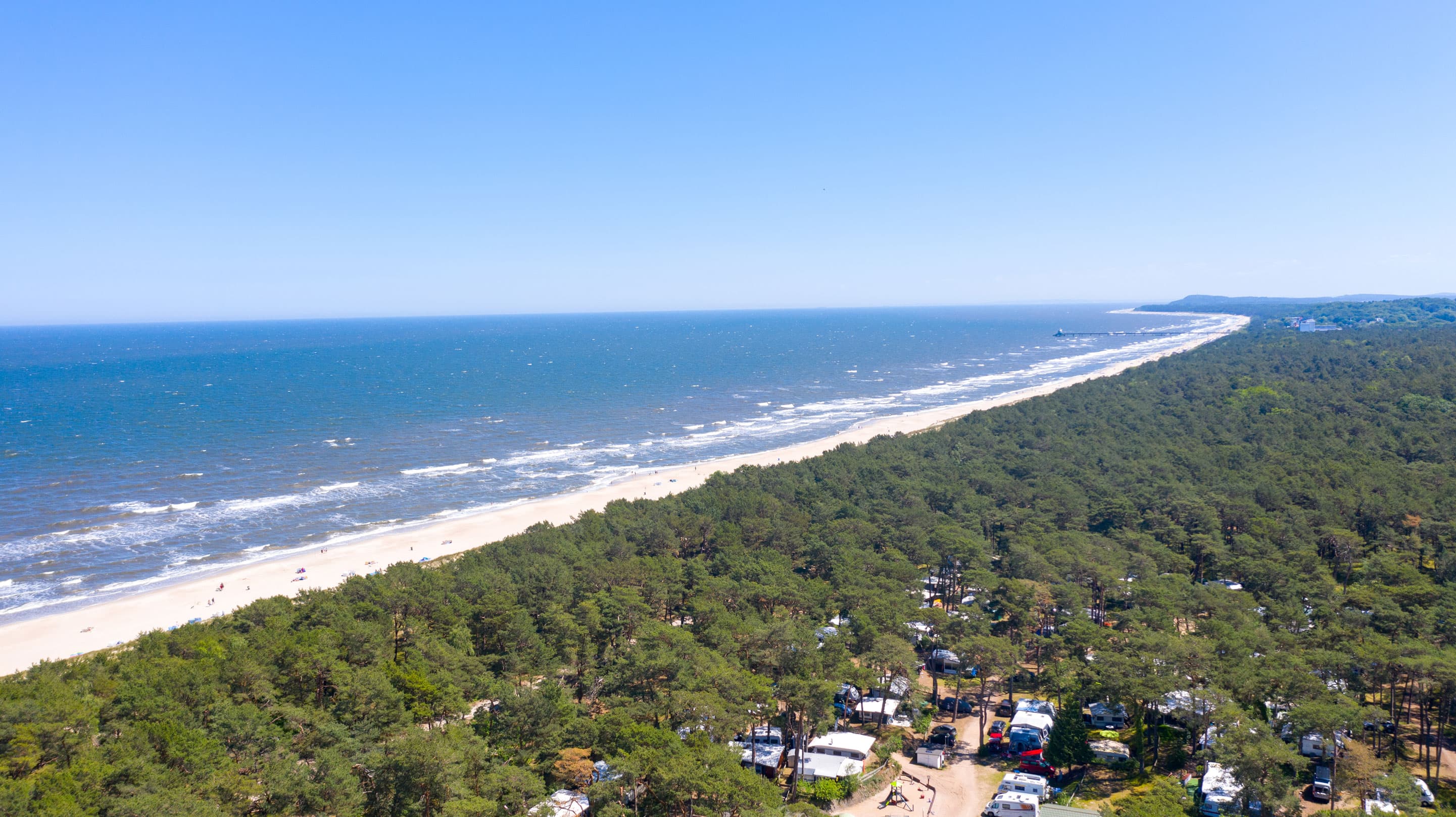 The photo shows an aerial view of the Baltic Sea resort of Trassenheide. The long beach and the extensive coastal forests are clearly visible.