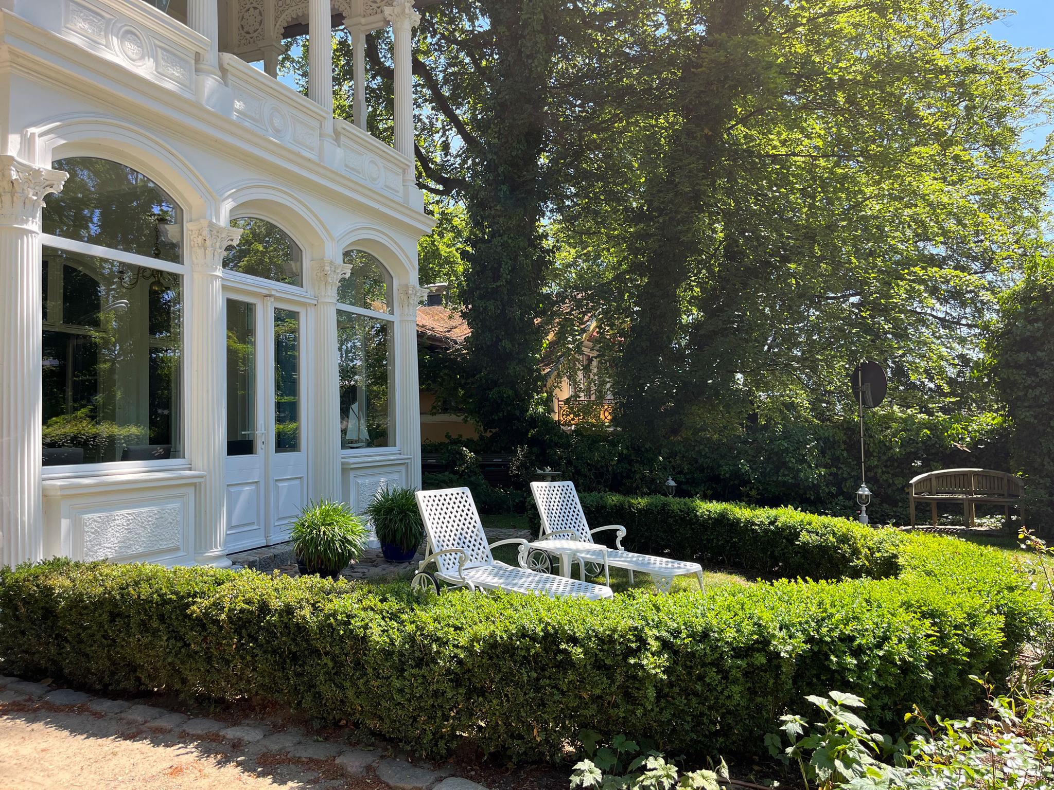 Gartenstühle vor einer Villa im Grünen