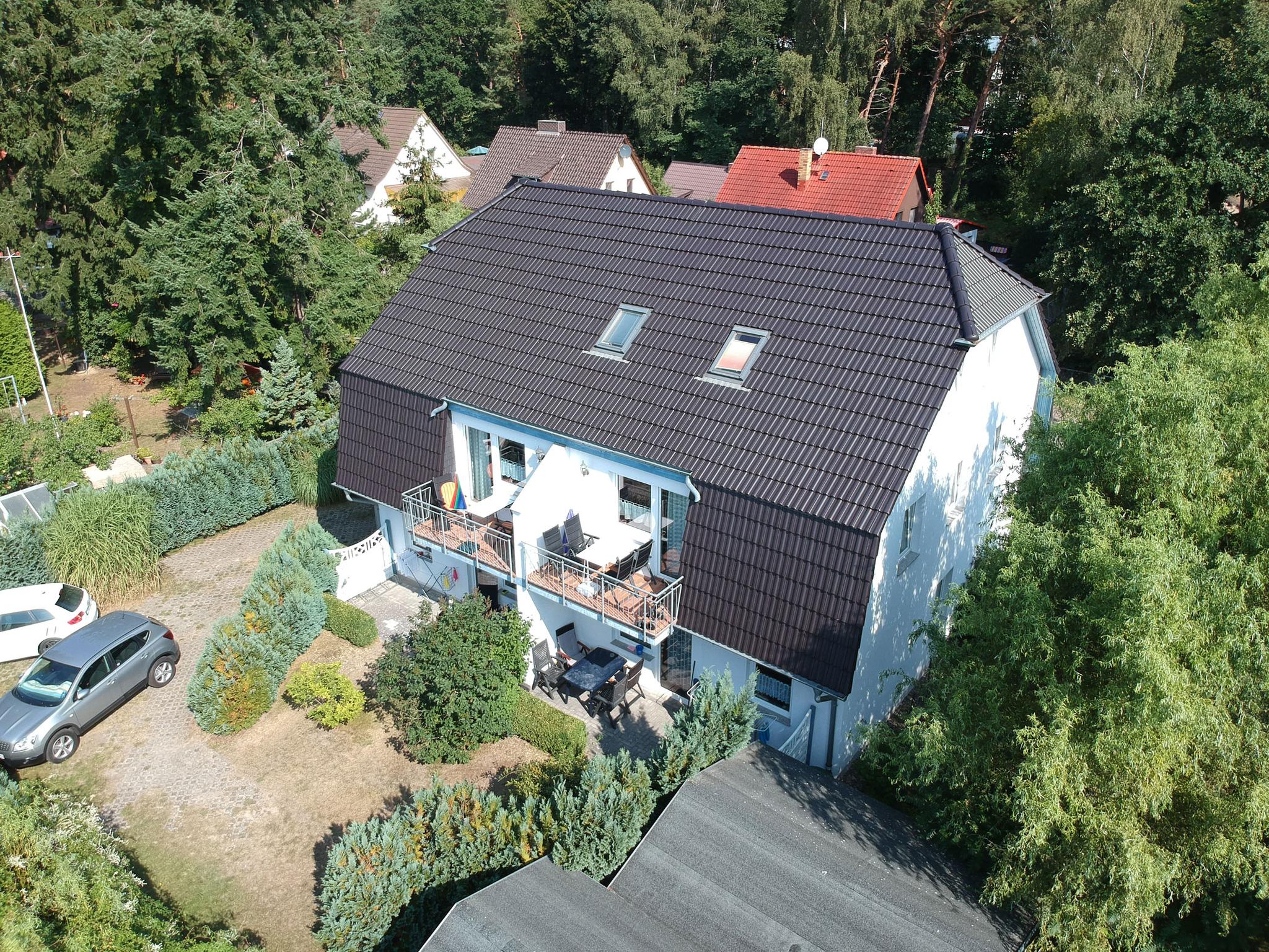 Haus mit grauem Dach von oben und umgeben von Wald
