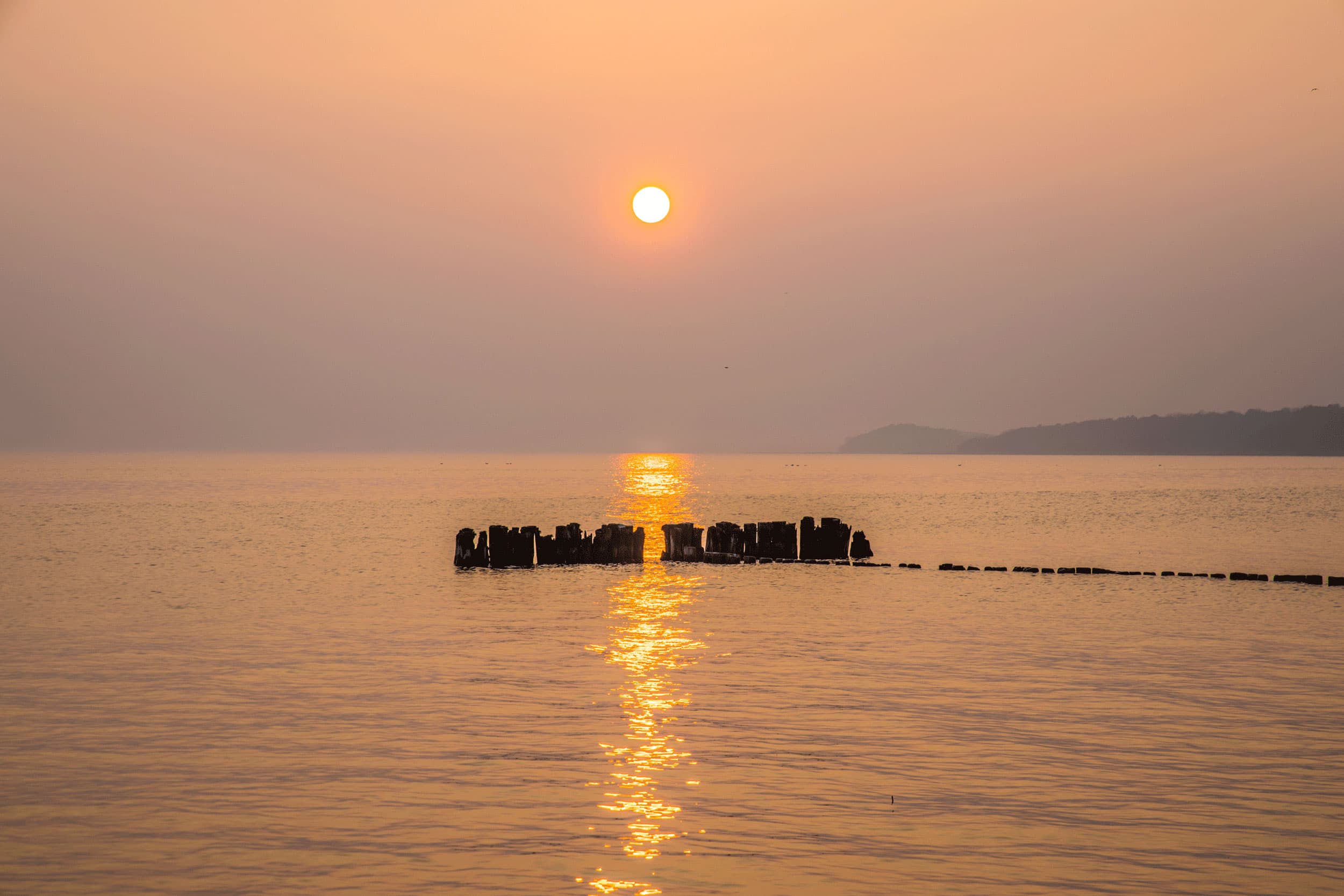 Das Bild zeigt den Sonnenuntergang über dem Stettiner Haff in Kamminke.