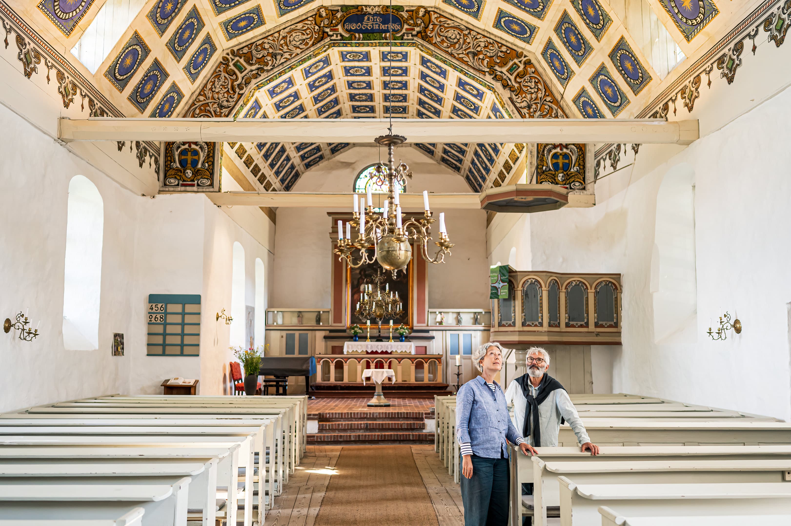 Pärchen steht in einer Kirche und blickt auf die bemalte Decke.