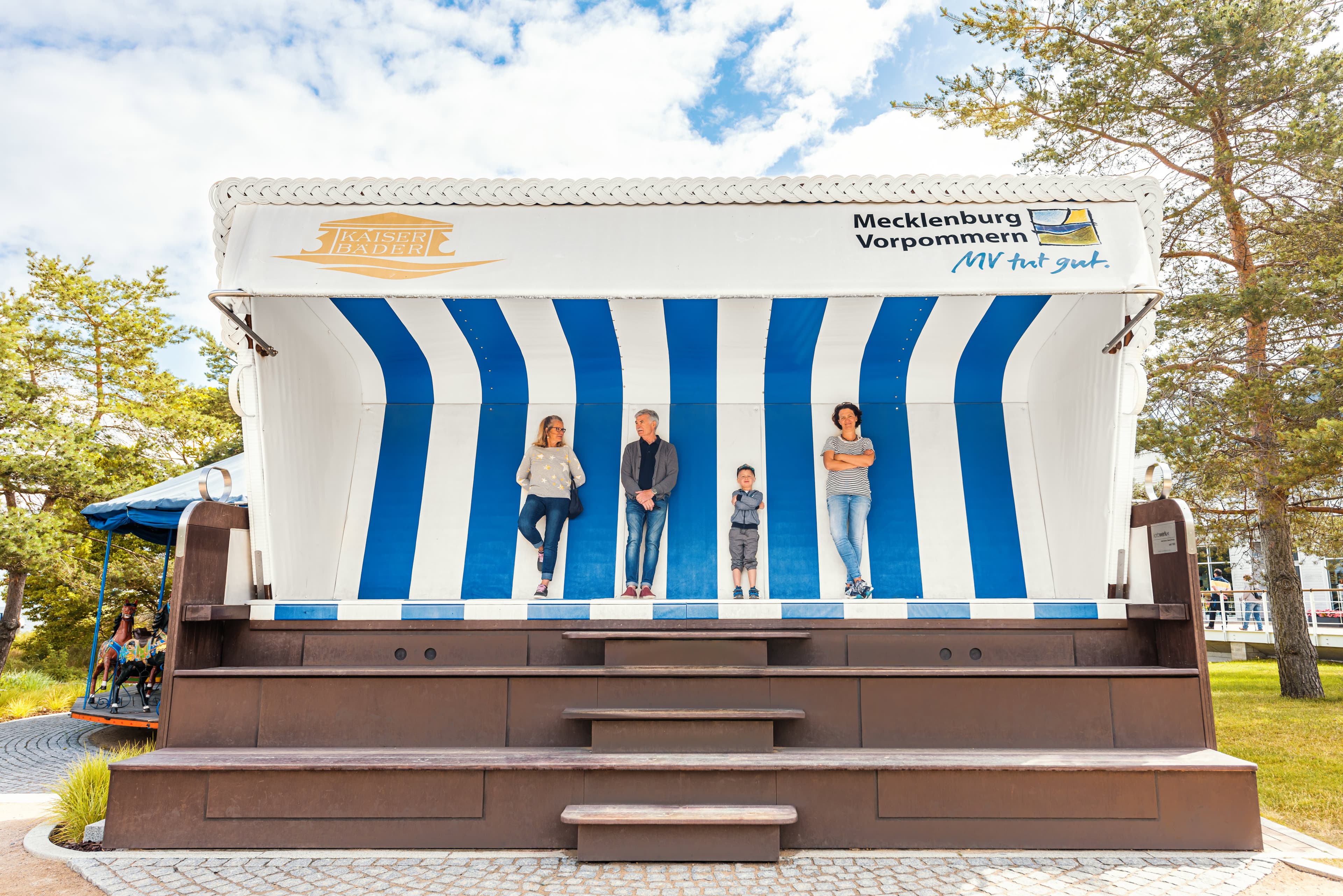 Personen stehen im blau-weißen XXL-Strandkorb