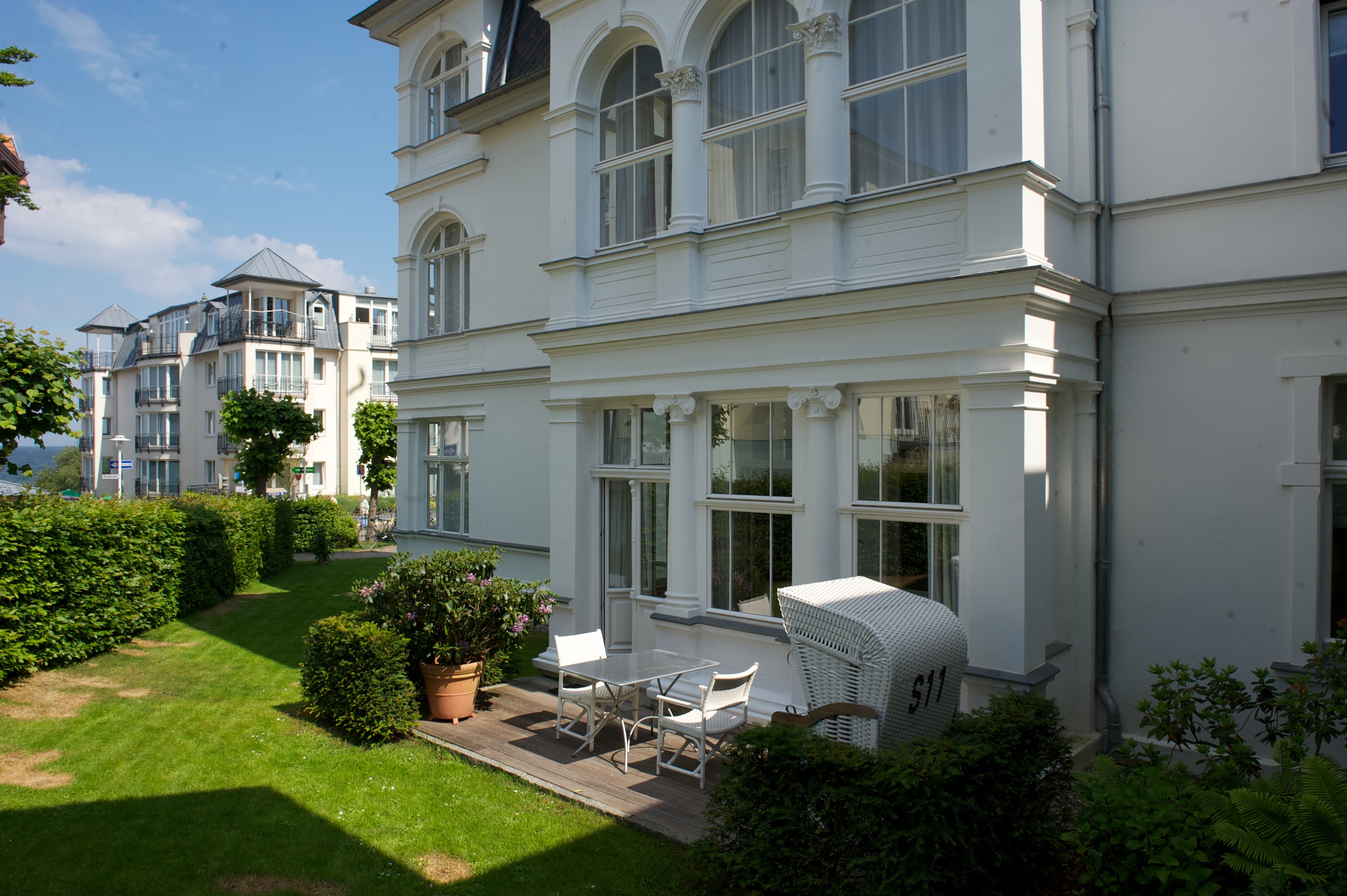 Terasse der Villa mit Gartenstühlen und einem Strandkorb.