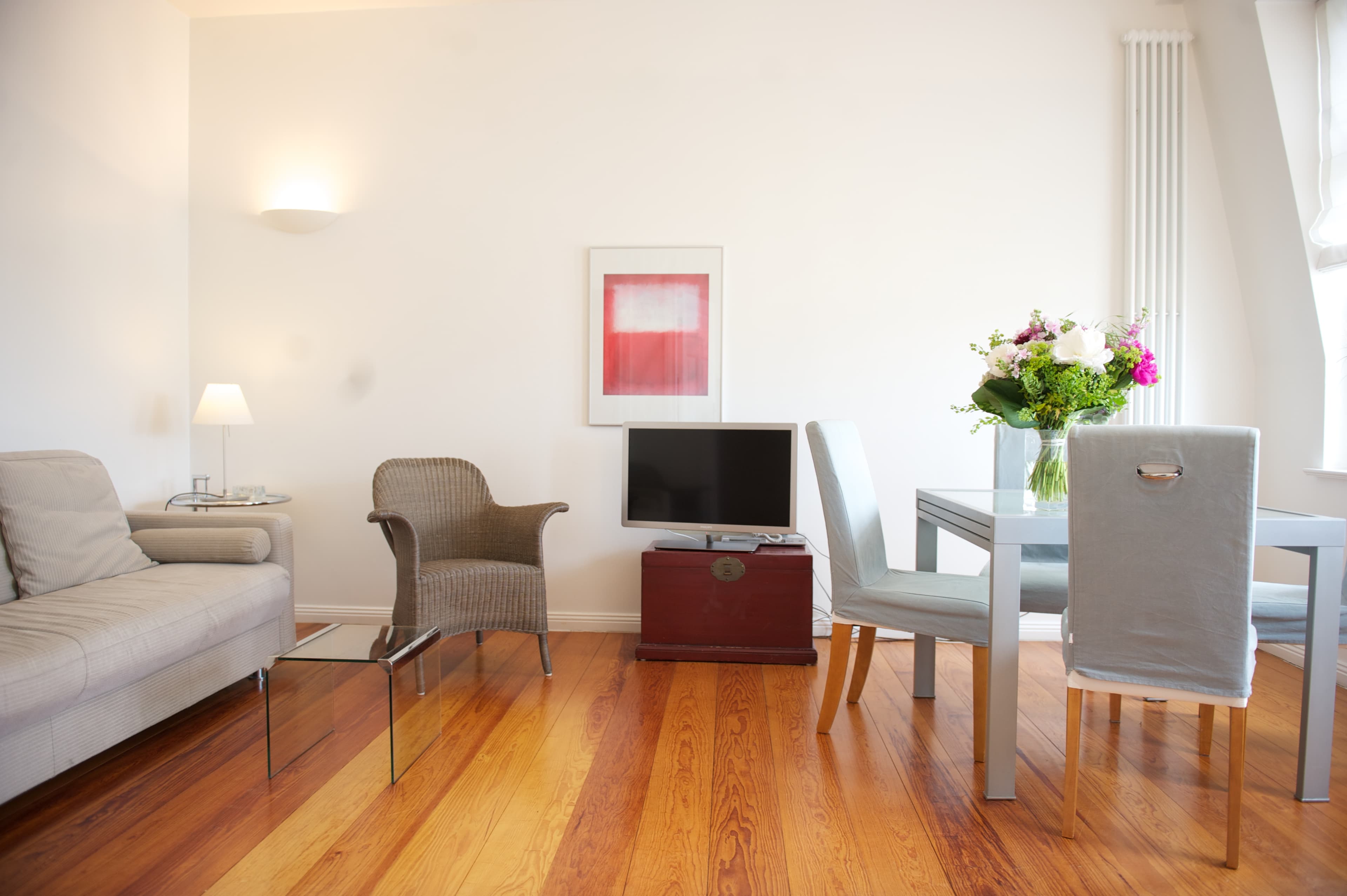 Wohn- und Esszimmer mit Holzfußboden und grauem Möbiliar