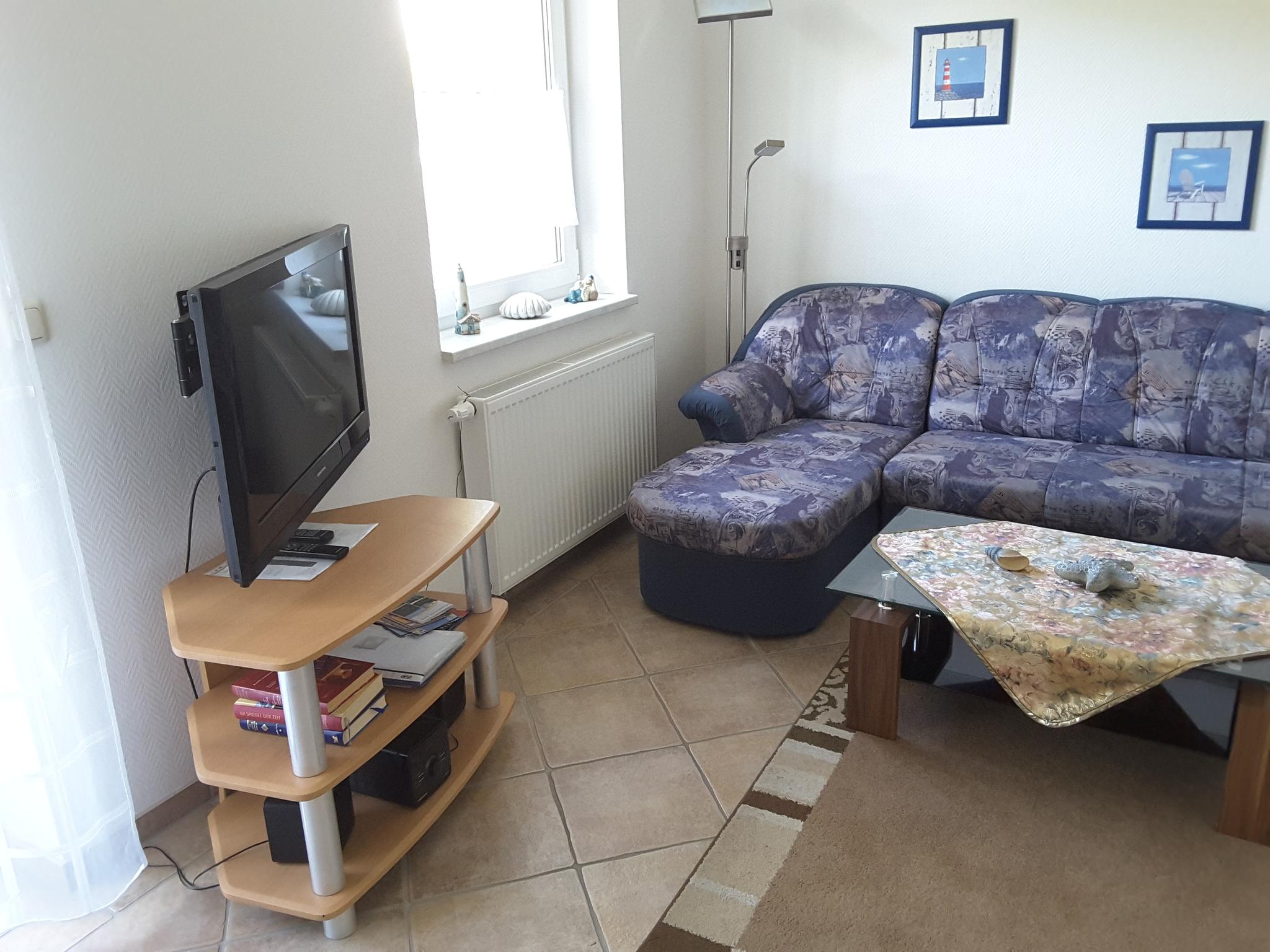 Wohnzimmer mit Eckcouch, Couchtisch und einem kleinen Fernseher.