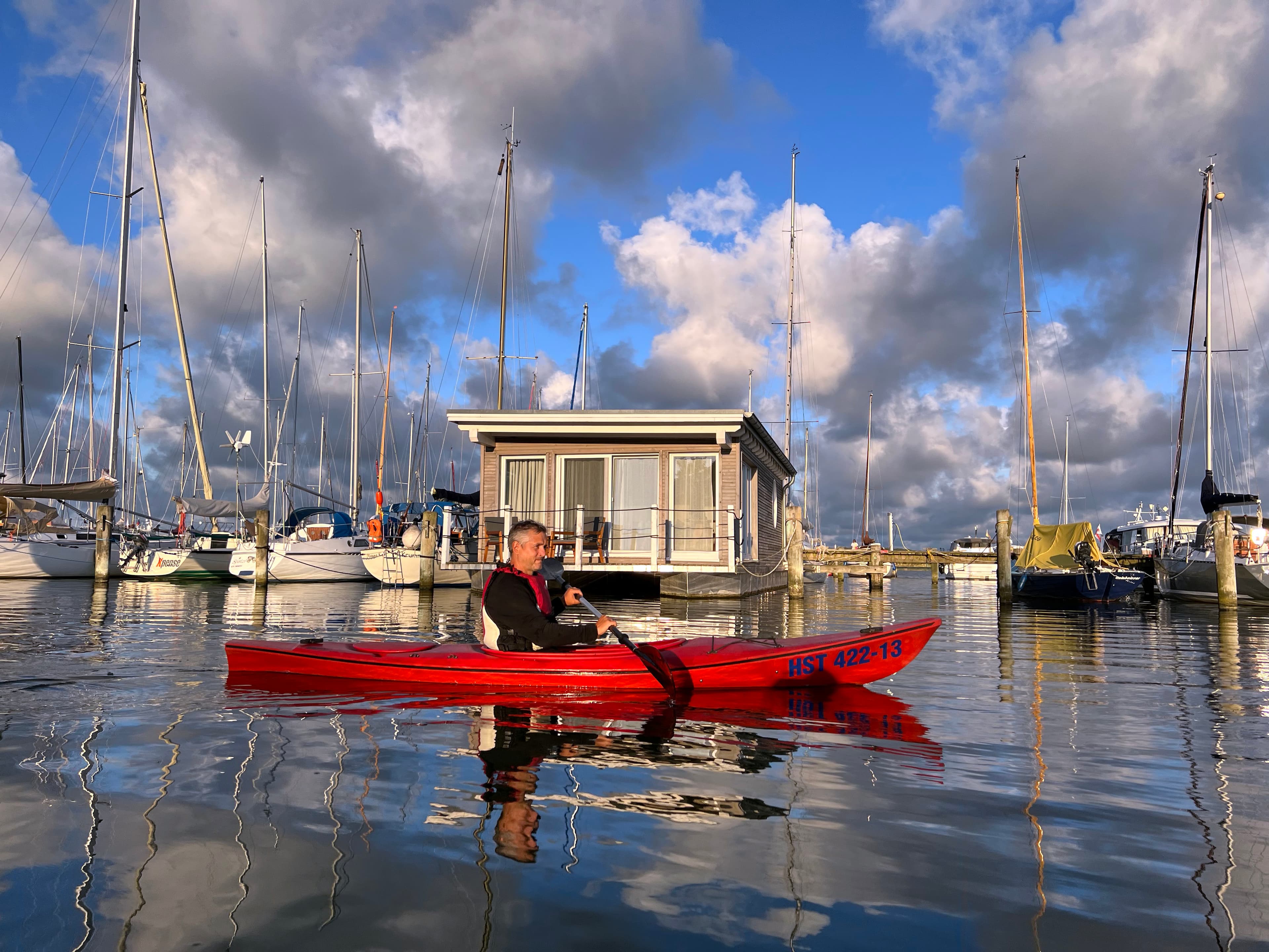 Mann fährt mit einem Kajak durch einen Hafen.