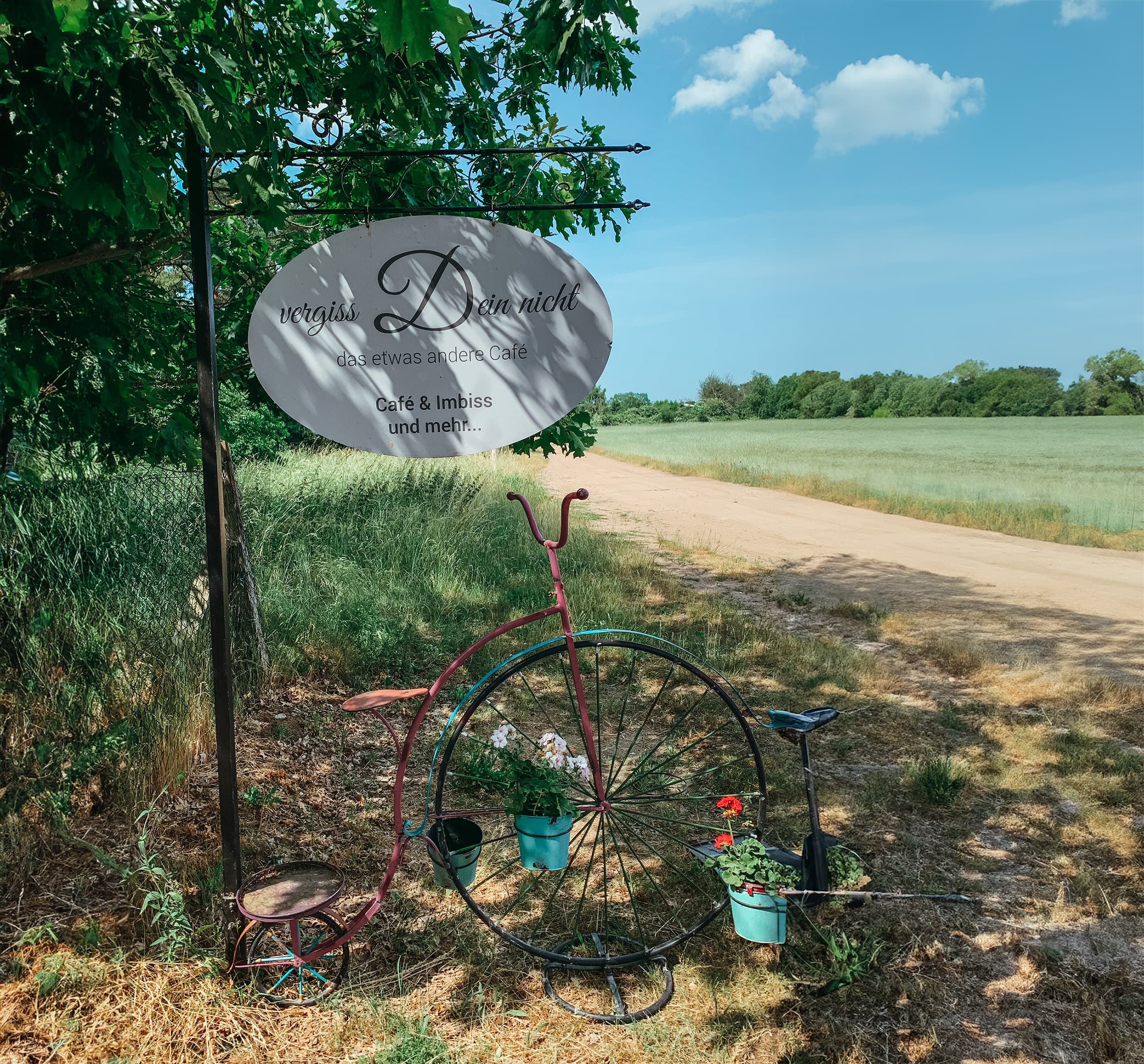 Café-Schild an einem Feldweg