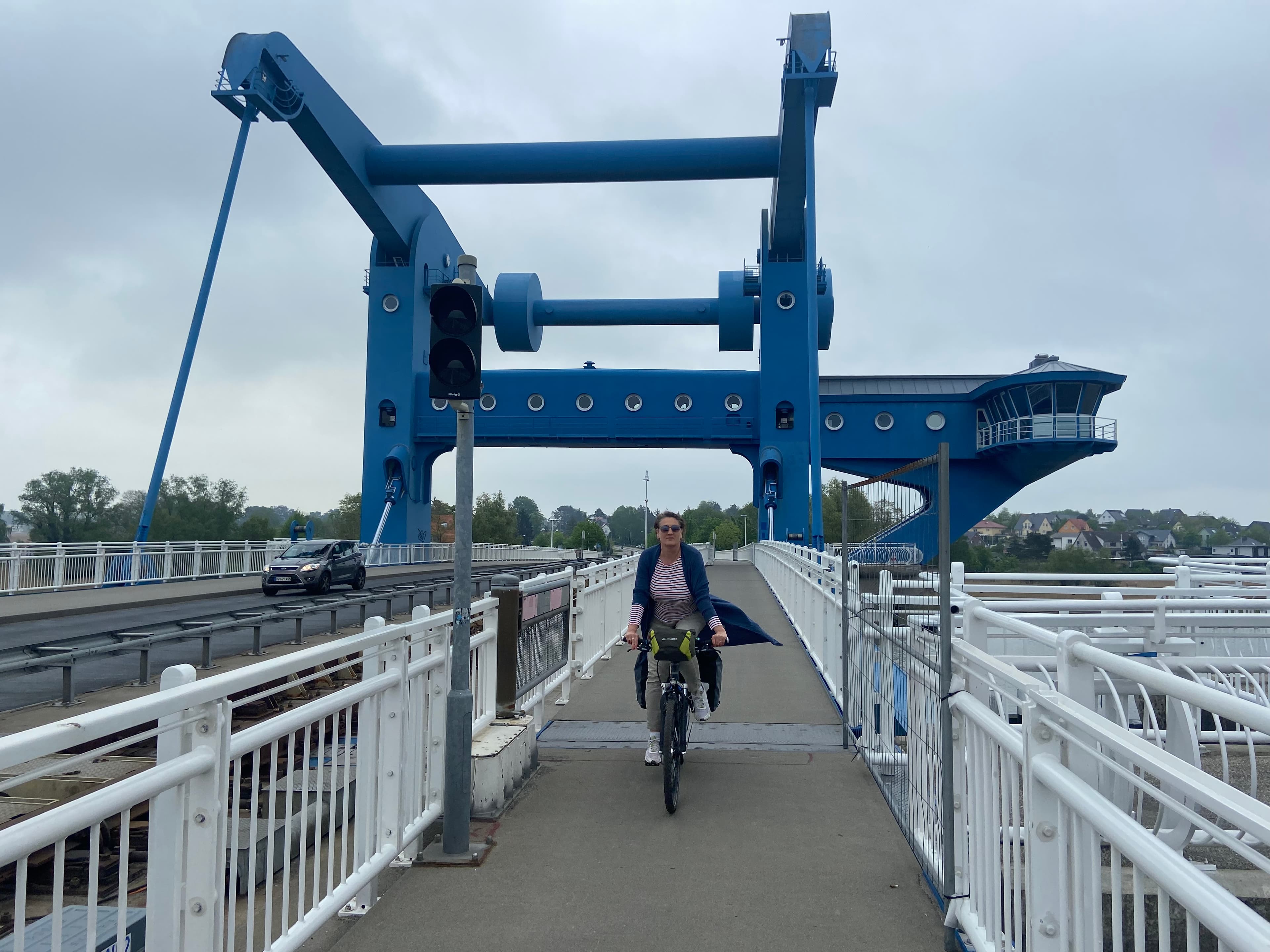 Frau fährt auf einem Fahrrad über die blaue Peenebrücke